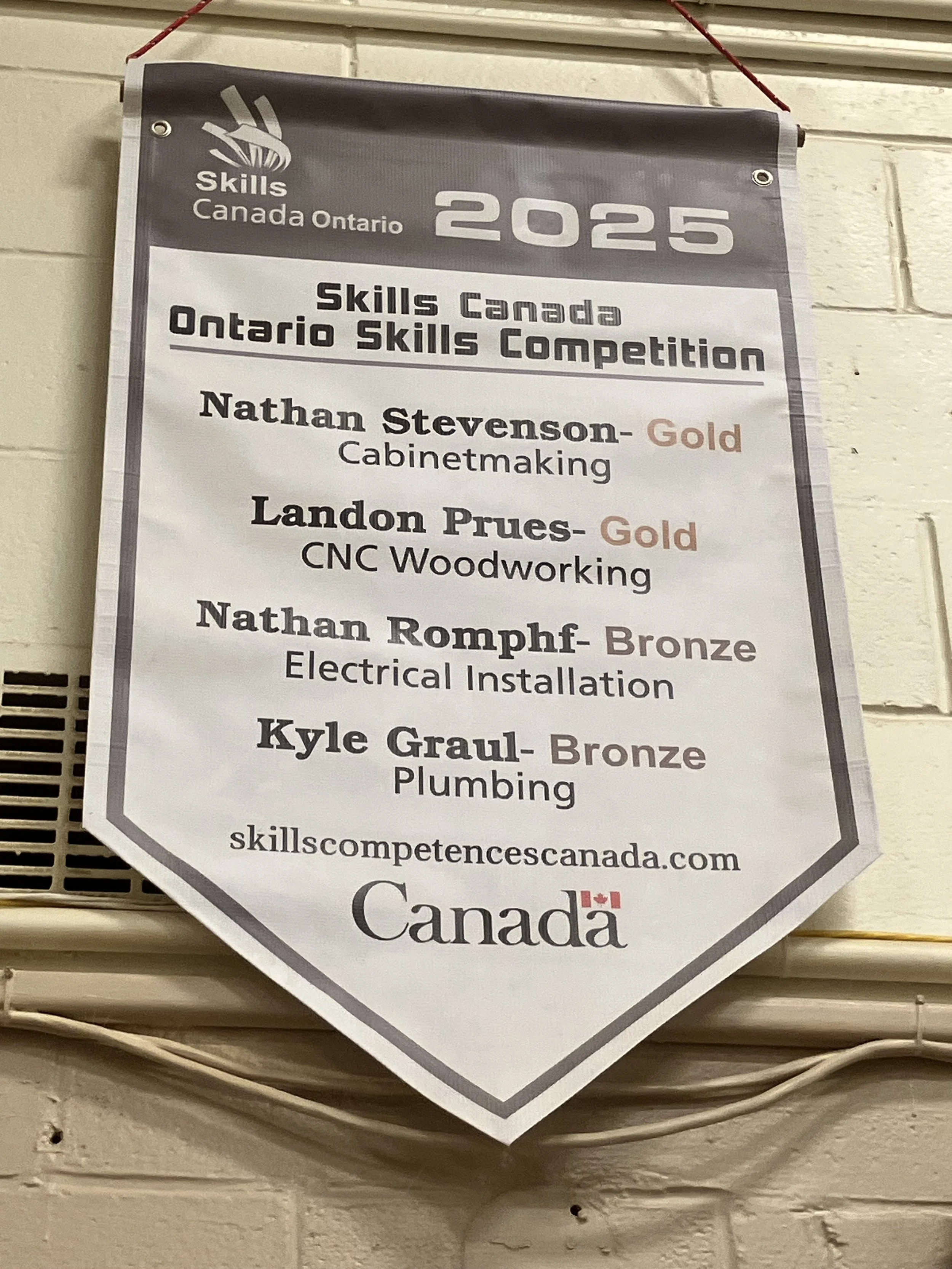 A banner for Skills Canada Ontario 2025, listing competitors and their skills including Nathan Stevenson in cabinetmaking, Landon Prues in CNC woodworking, Nathan Romphf in electrical installation, and Kyle Graul in plumbing - Signupsigns - Neustadt.