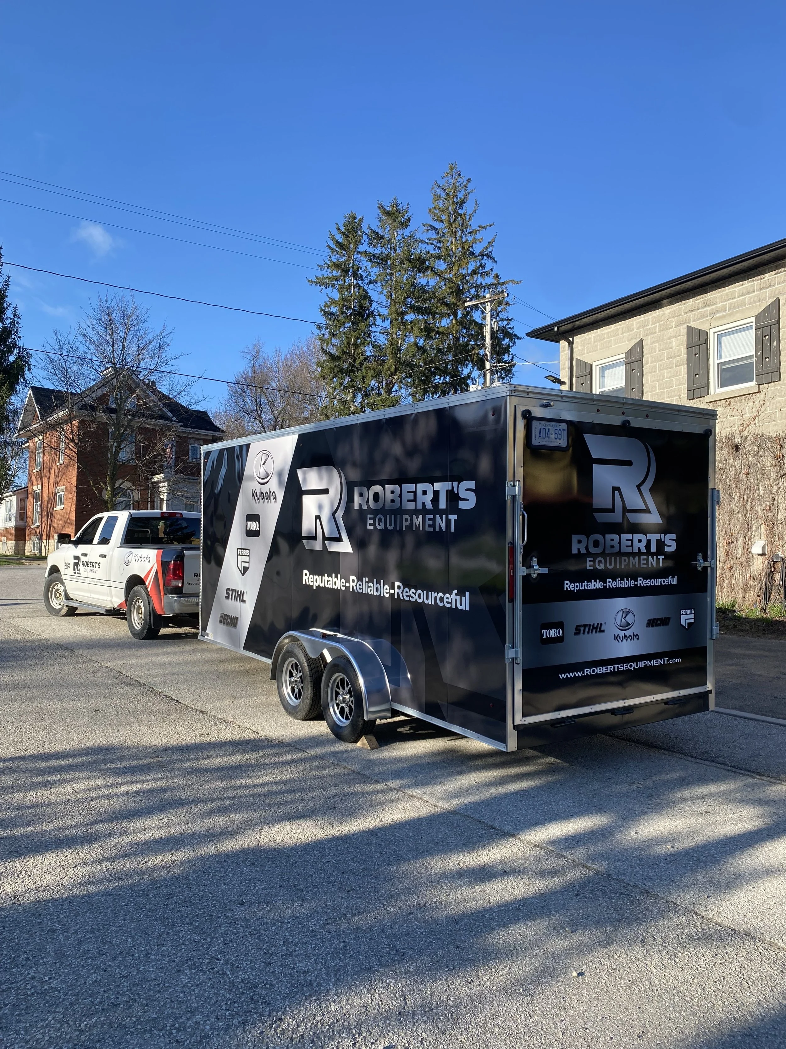 A white utility truck and a black enclosed trailer with logos and text for Roberts Equipment parked on a residential street. The trailer features brand logos and the slogan 'Reputable Reliable Resourceful.' - Signupsigns - Neustadt.