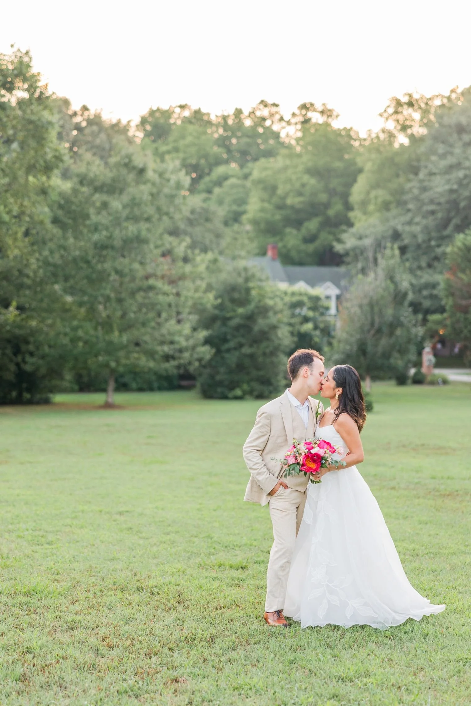 Bride and groom kiss in the open field landscape of Historic Jasmine, a picturesque wedding venue in New Kent VA.