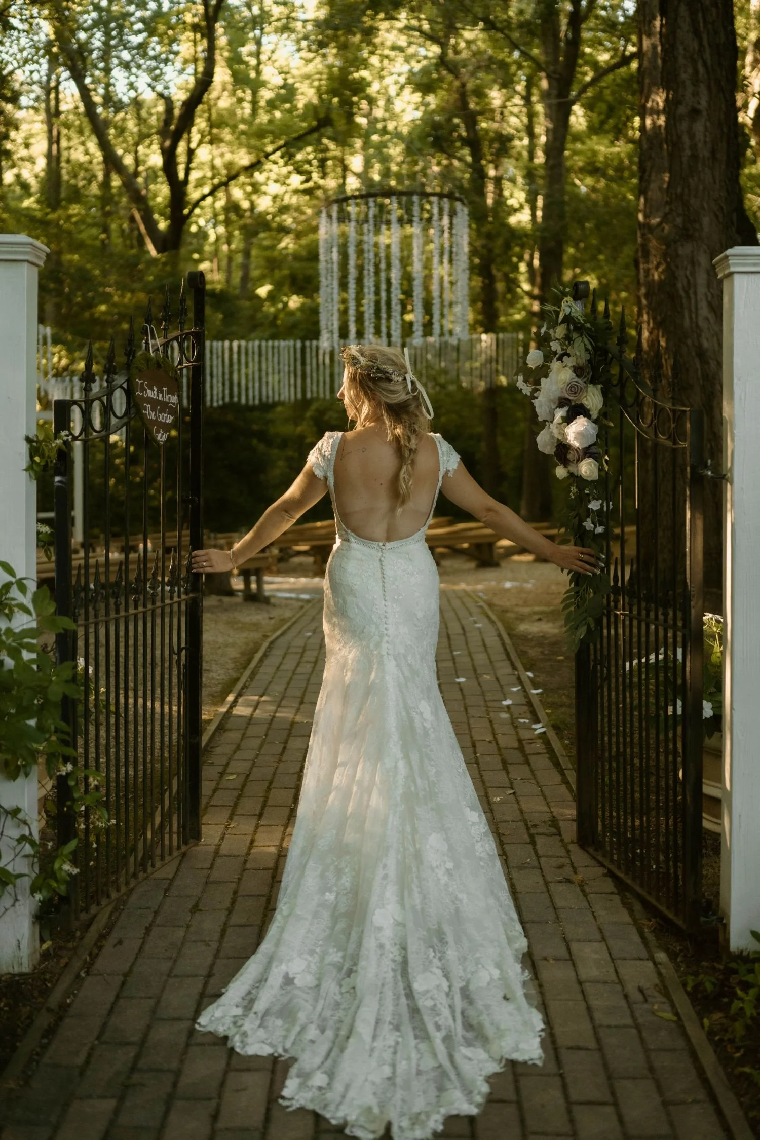 A bride opens the entrance gates to the Chapel in the Woods ceremony site located at Historic Jasmine,  a woodland fairytale wedding venue in New Kent, Virginia.