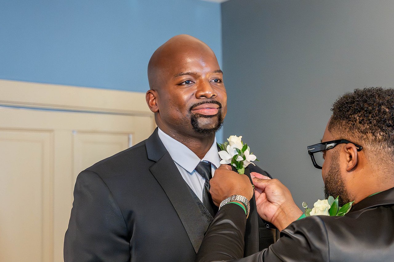 Groom puts on boutonniere in the Study before the wedding ceremony | Historic Jasmine, a private wedding venue in New Kent, Virginia.