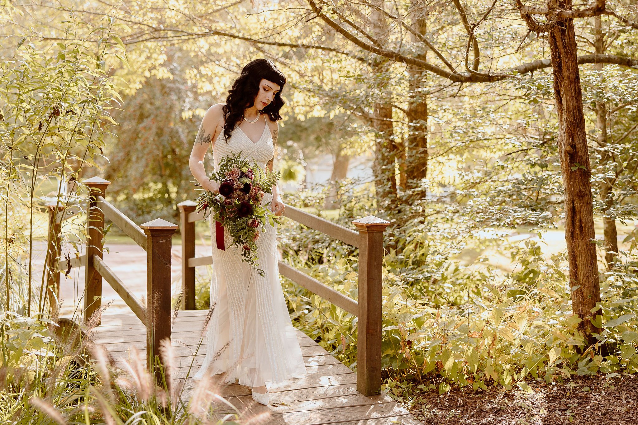 A bride walks across the lover's bridge in the secret gardens located at Historic Jasmine, a private wedding venue in New Kent, Virginia.
