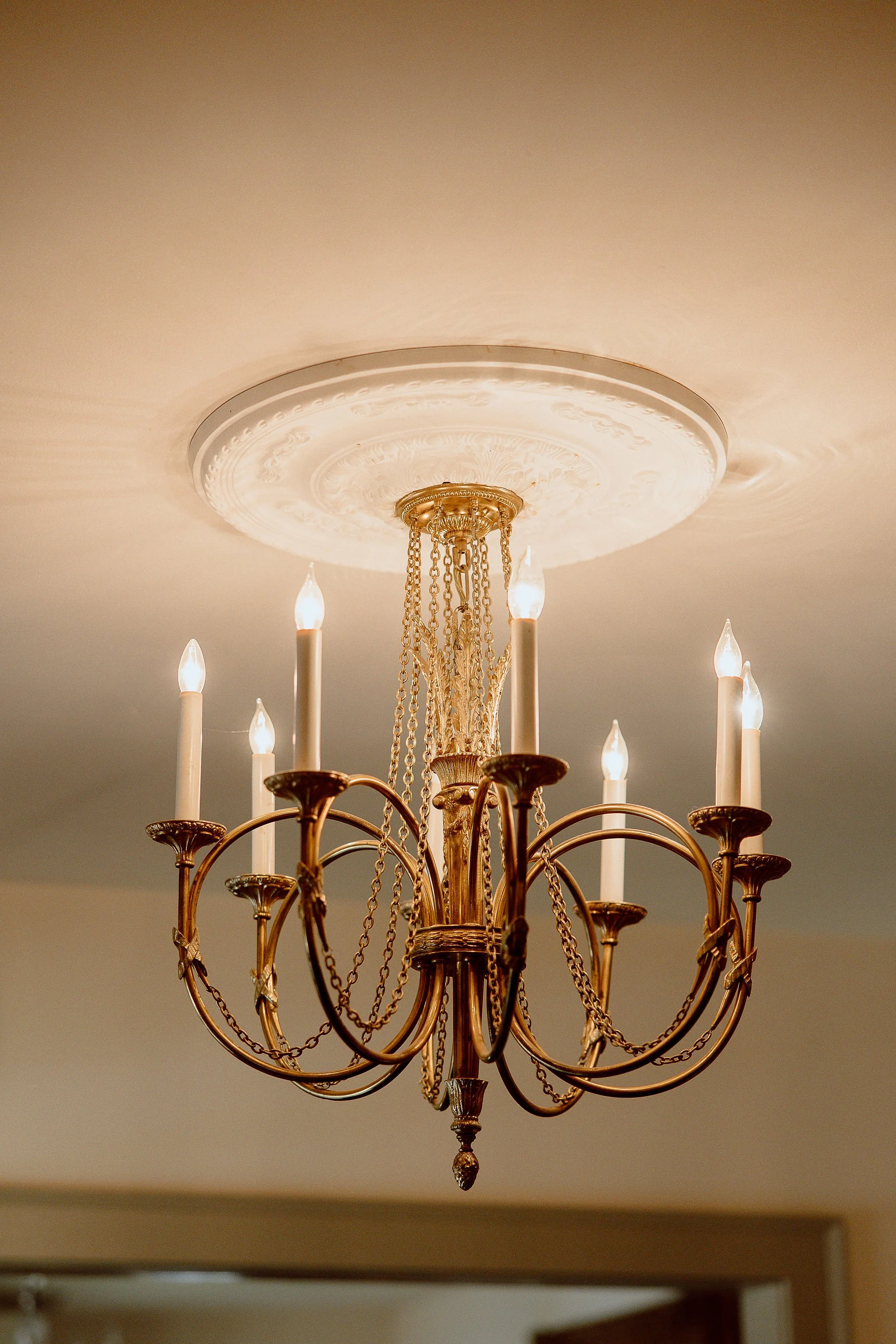 Detailed view of a gold chandelier in the Manor House located at Historic Jasmine, a private wedding venue in New Kent County, Virginia.