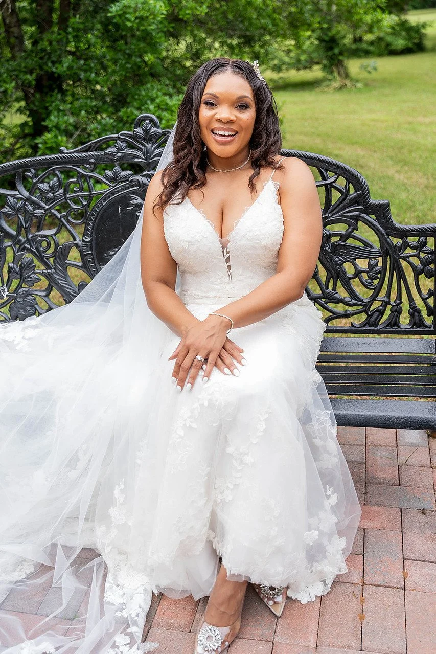 A bride poses on a wrought iron bench in the garden | Historic Jasmine, a private wedding venue in New Kent, Virginia.