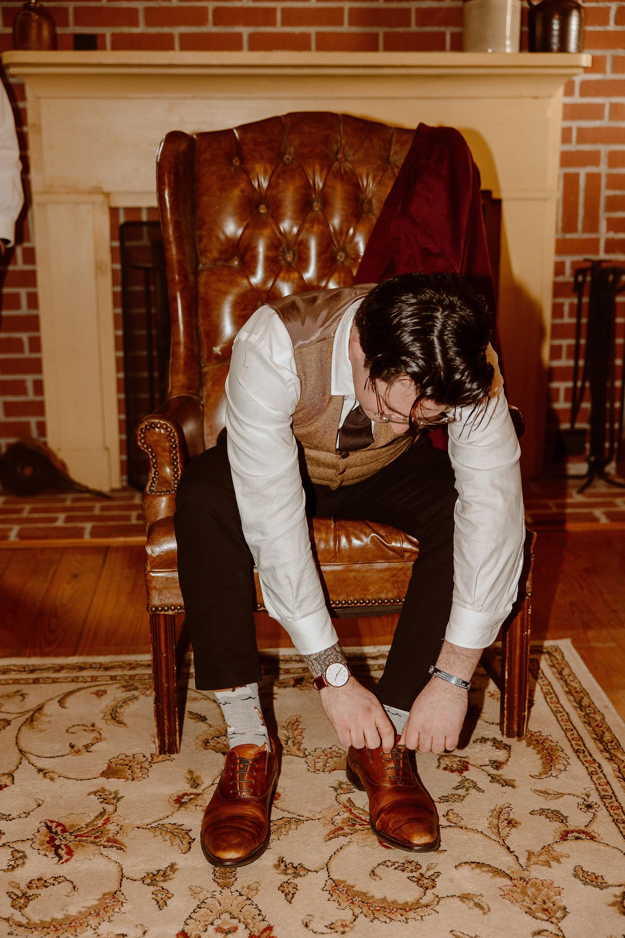 Groom laces his dress shoe before the wedding ceremony at Historic Jasmine, a private wedding venue in Greater Richmond, Virginia.