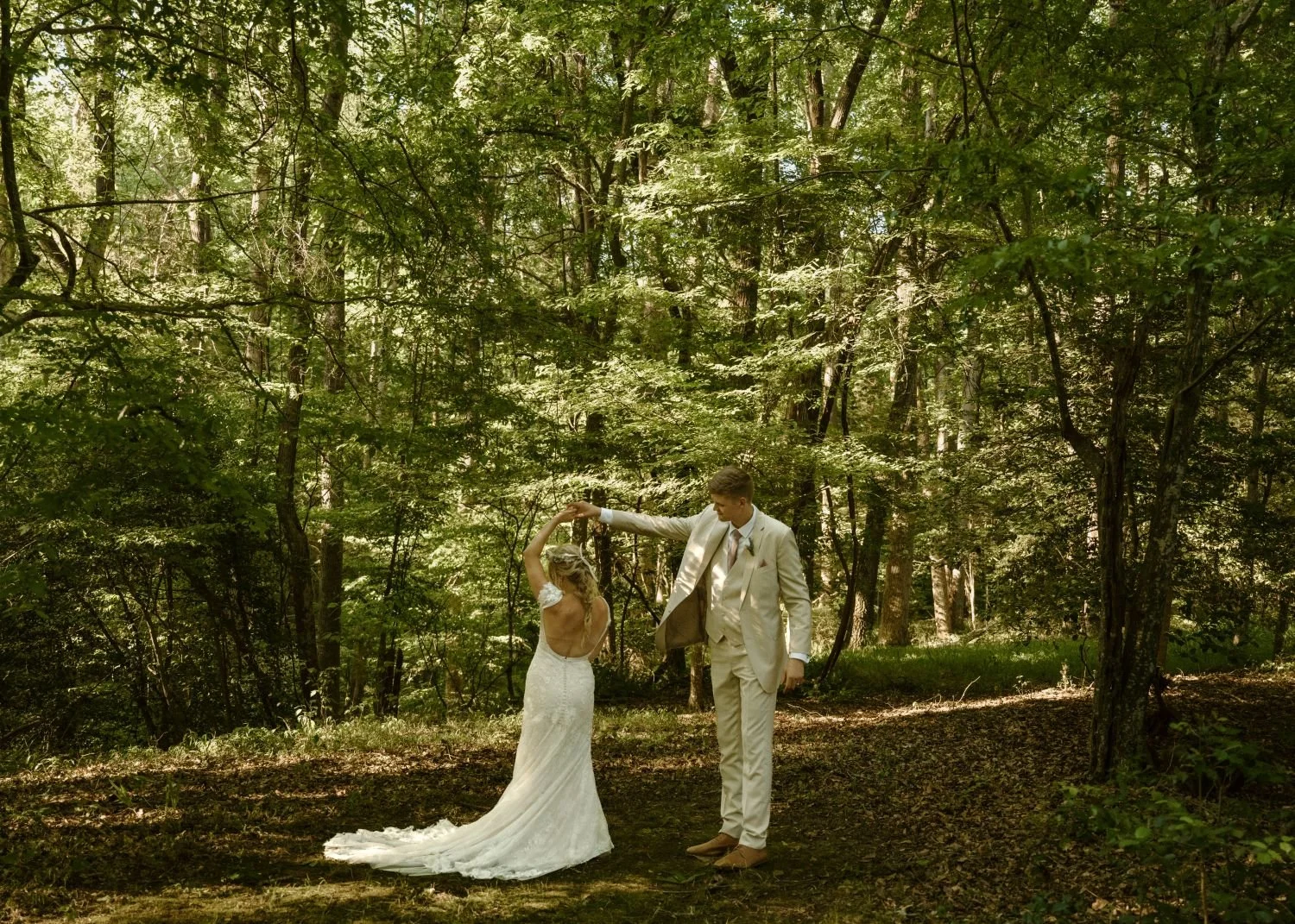 A bride and groom dance in the forest as the sunlight filters through the canopy. Historic Jasmine, a dreamy fairytale wedding venue near Richmond, VA. 