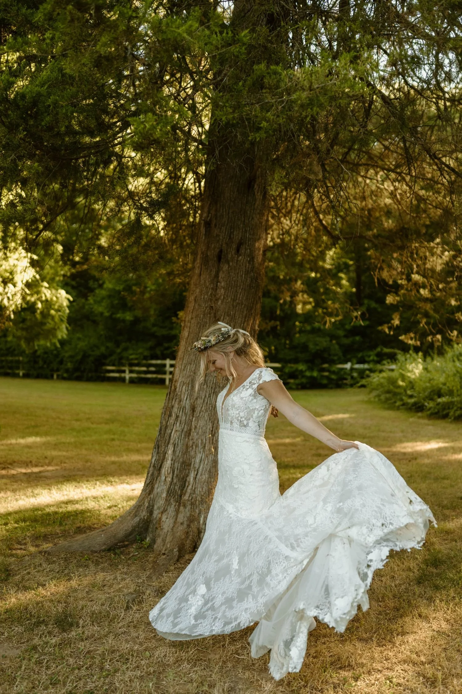 A boho bride dances around a cedar tree located at Historic Jasmine, a romantic garden wedding venue near Richmond, Virginia.