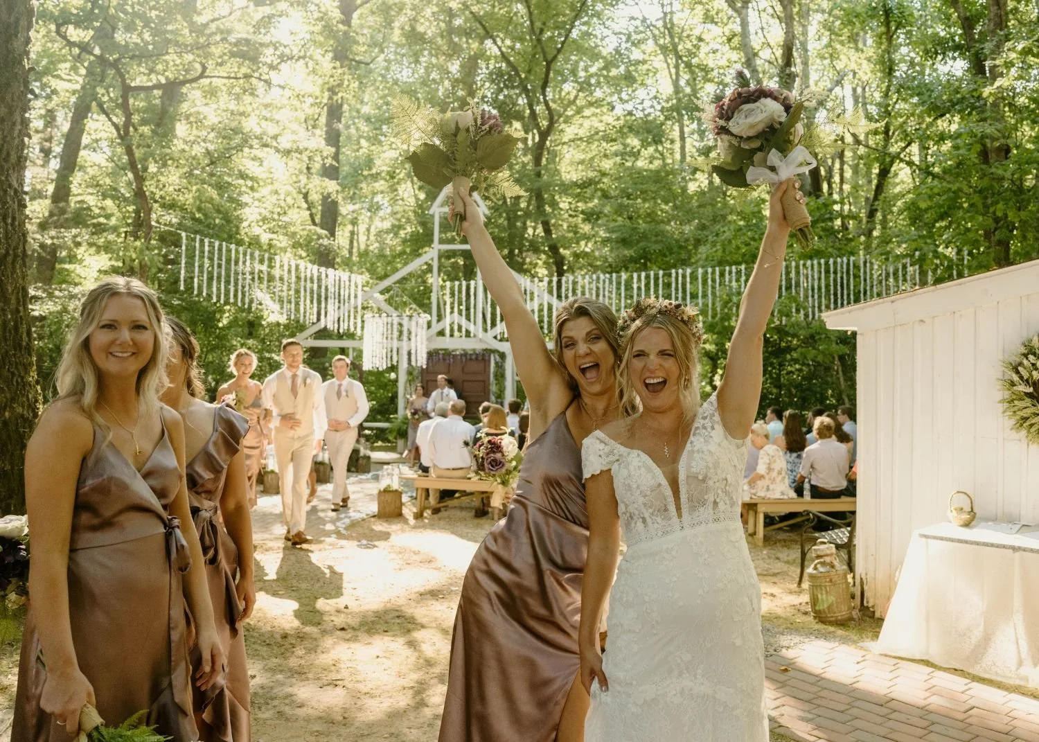 A bride and bridesmaid celebrate after a Chapel wedding located at Historic Jasmine, a woodland forest wedding venue in New Kent, Virginia.