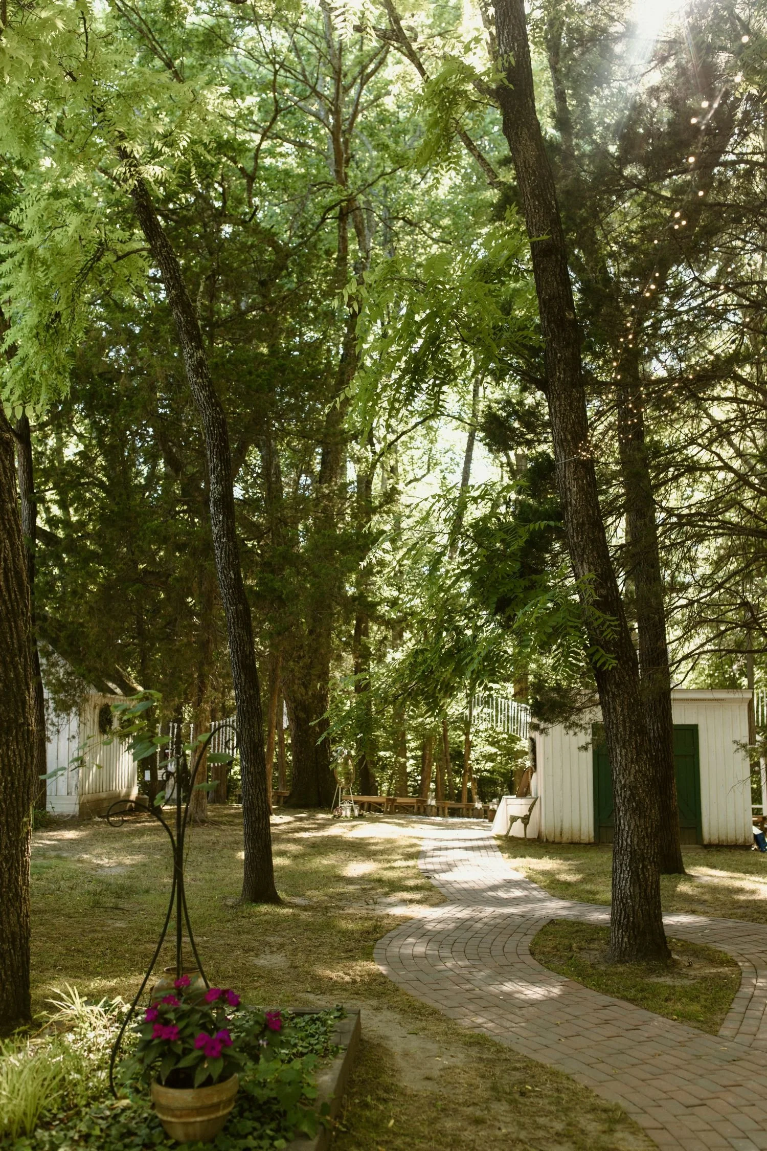 View of a serpentine brick pathway leading the fairytale chapel ceremony site located at Historic Jasmine, a wedding venue near Richmond, Virginia.