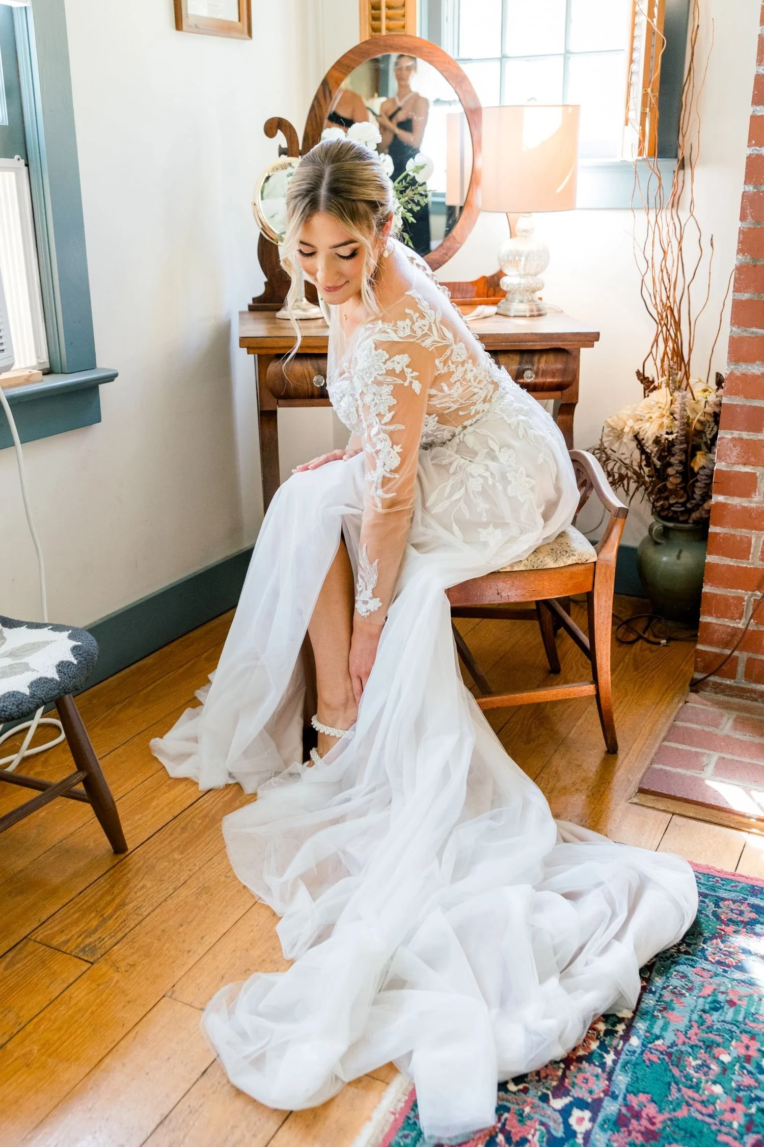 A bride in a lace wedding down prepares for the ceremony in the guest changing suite. Historic Jasmine is a garden wedding venue located New Kent, Virginia.