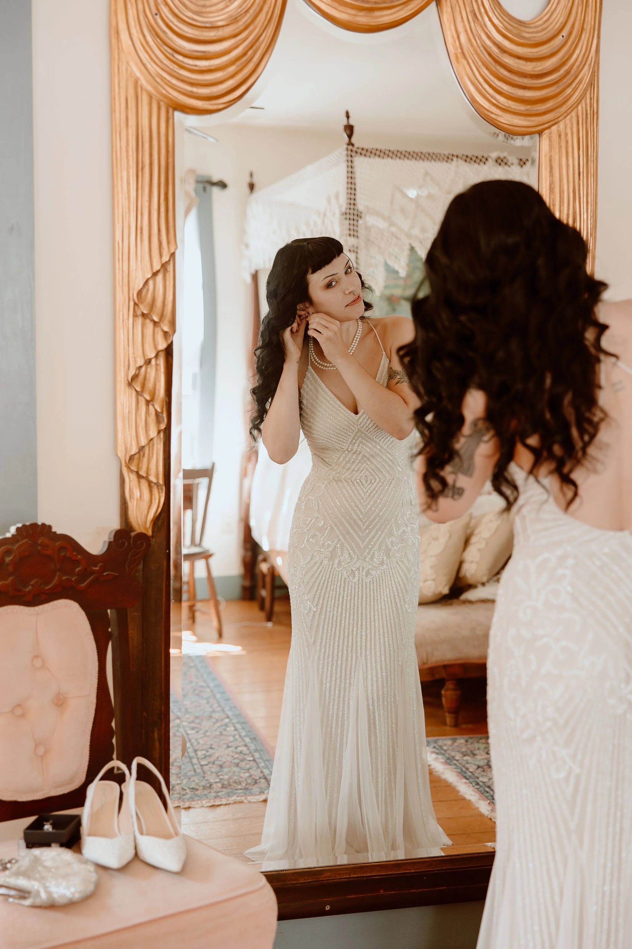 A bride puts on her earrings in bridal suite before the wedding ceremony at Historic Jasmine, a private wedding venue in Greater Richmond, Virginia.