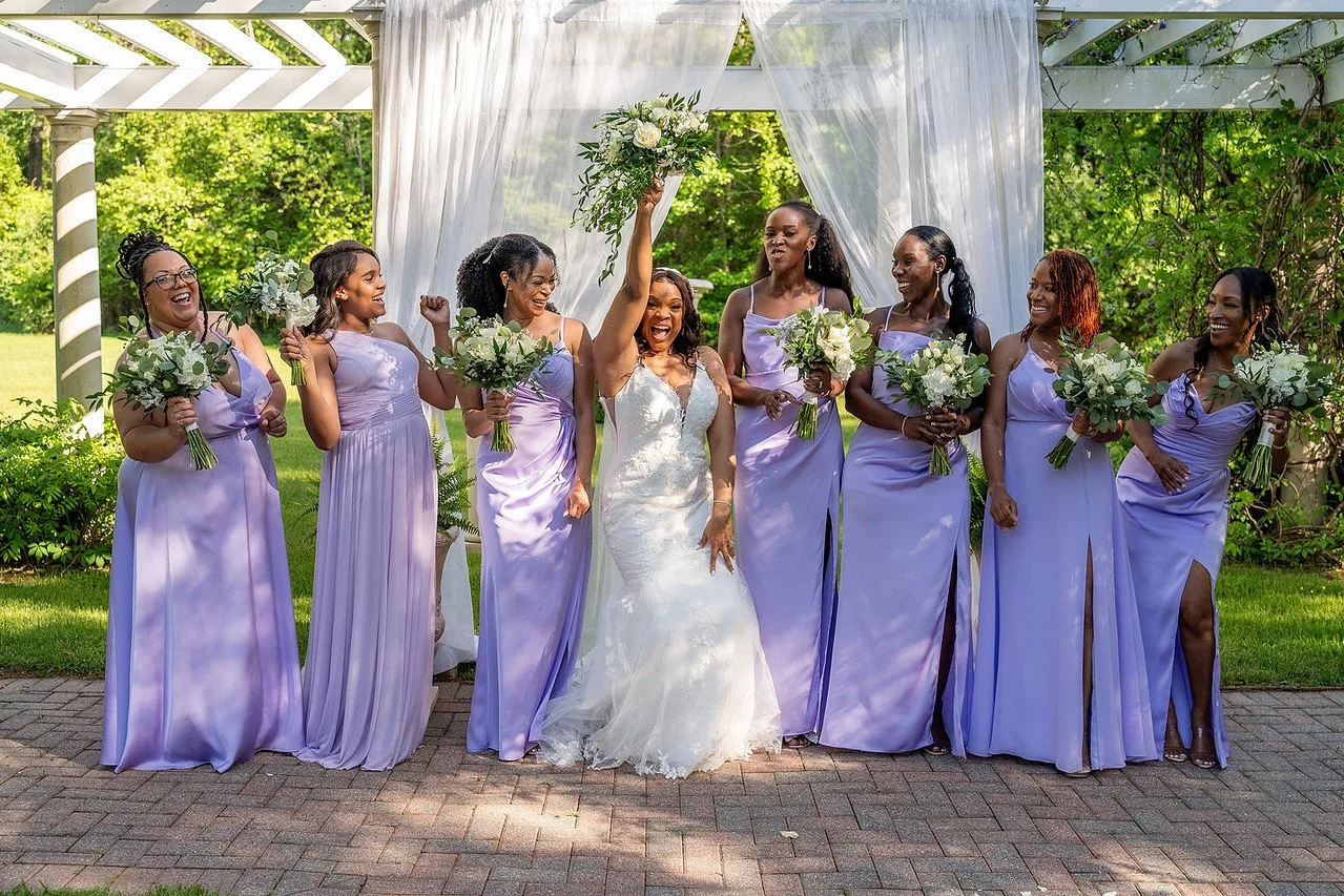 A bride and bridesmaid celebrate in front of the Garden Pergola ceremony site | Historic Jasmine, a private wedding venue in New Kent, Virginia.
