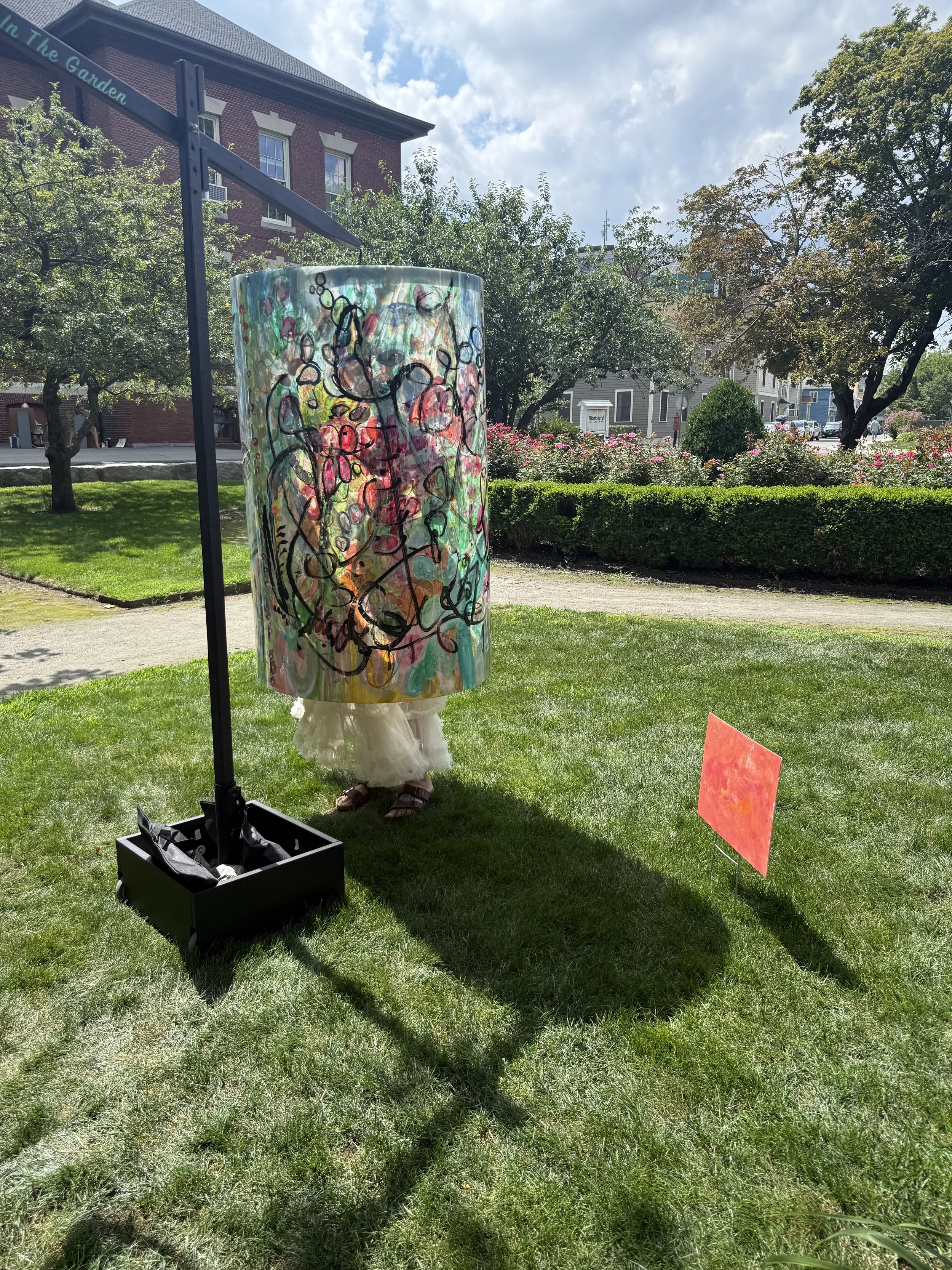 Freestanding multicolored painted panel sculpture on a black base in a park.