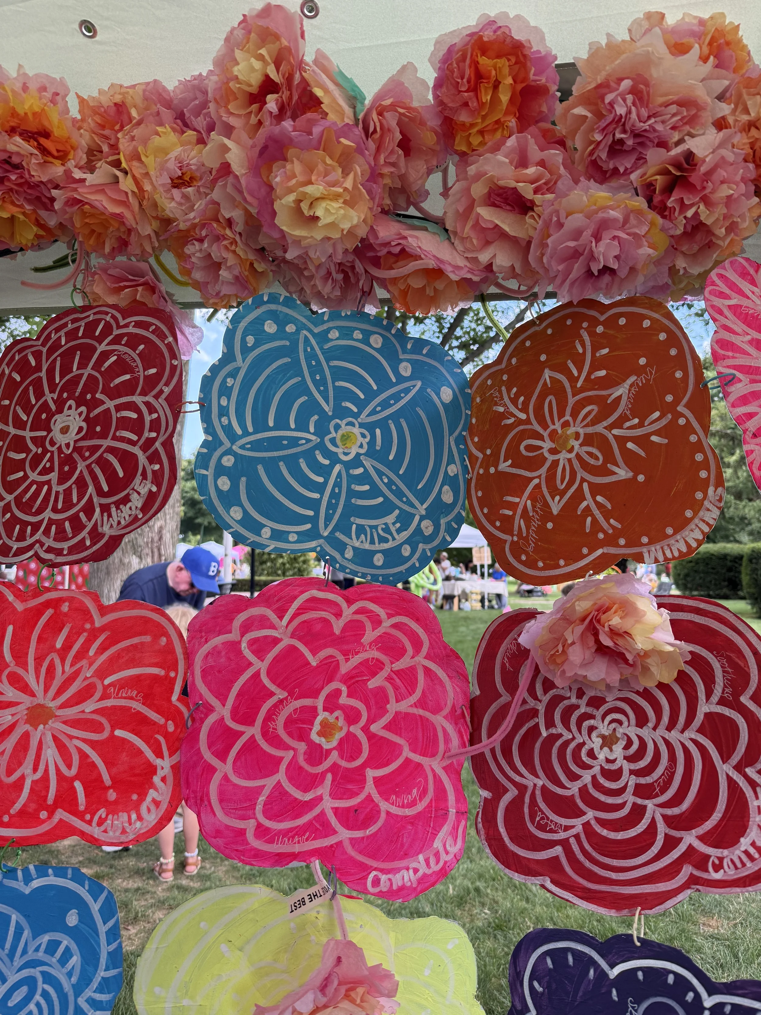 Close-up of painted circular floral forms in red, pink, blue, and orange on translucent material.