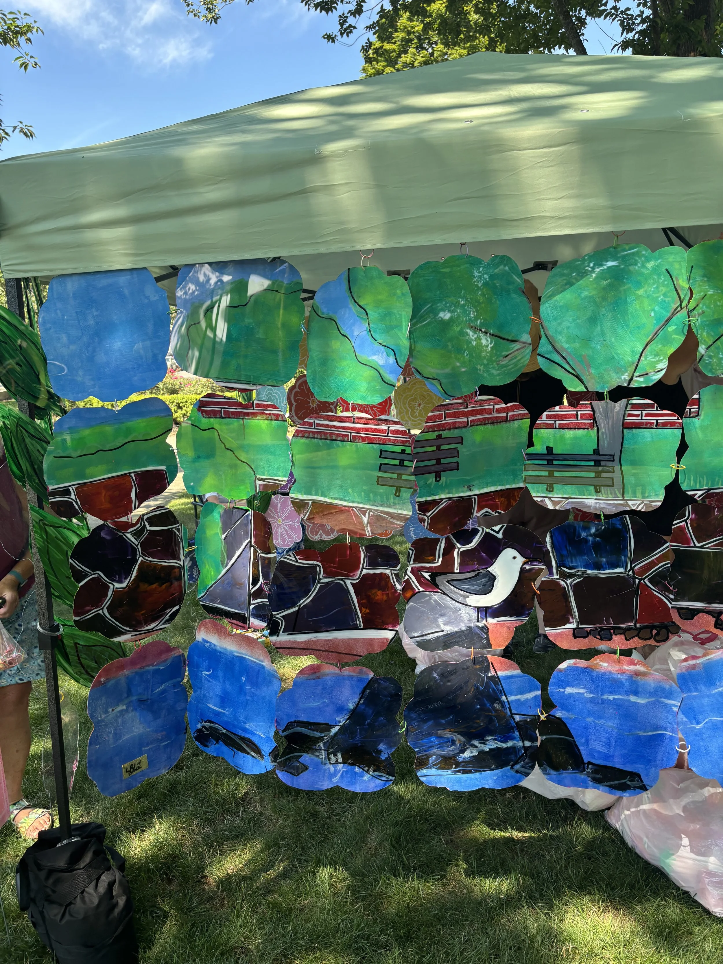 Close-up of overlapping green and blue painted translucent panels suspended under the canopy.