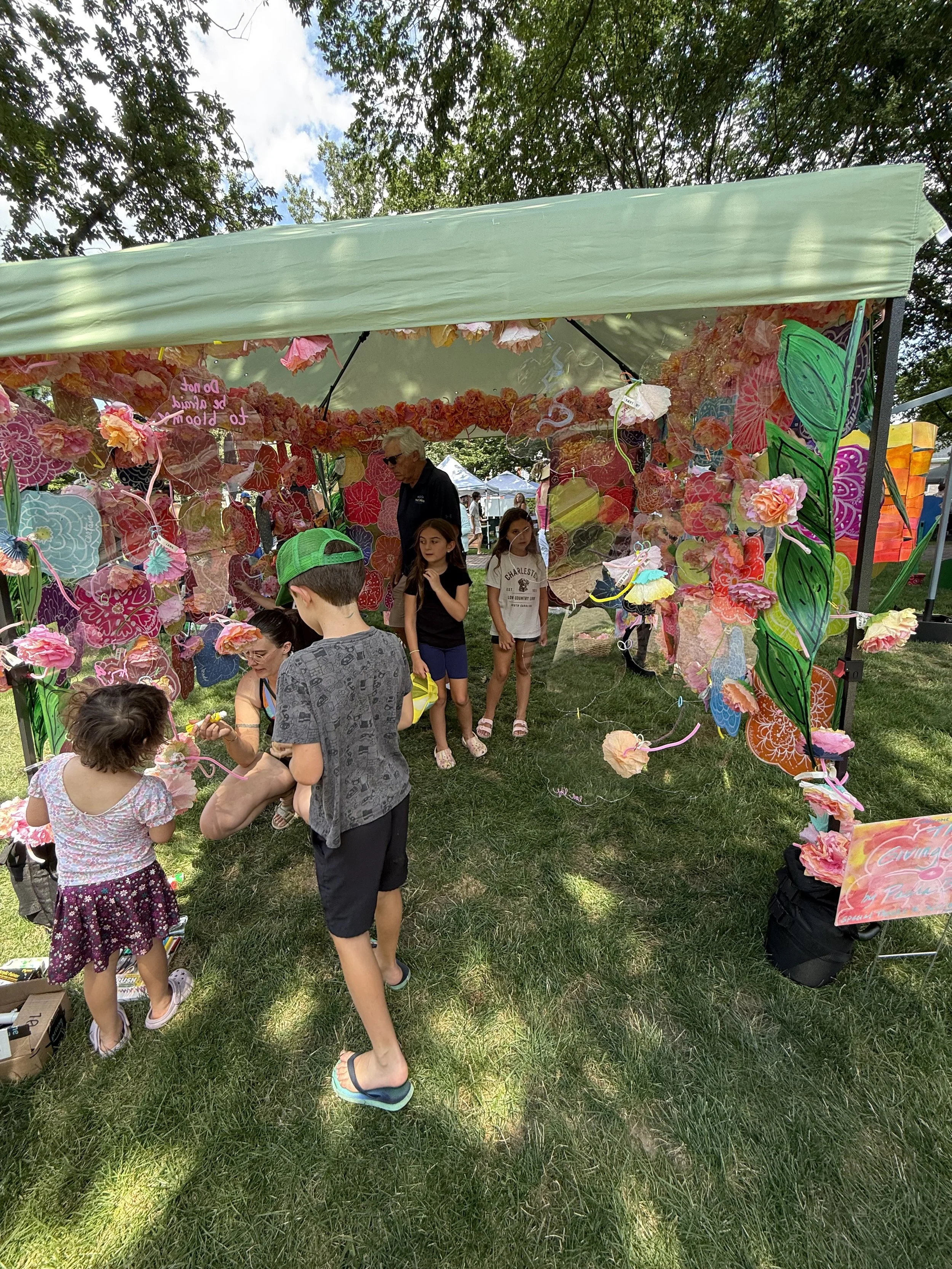 Visitors interacting with the colorful canopy installation outdoors.