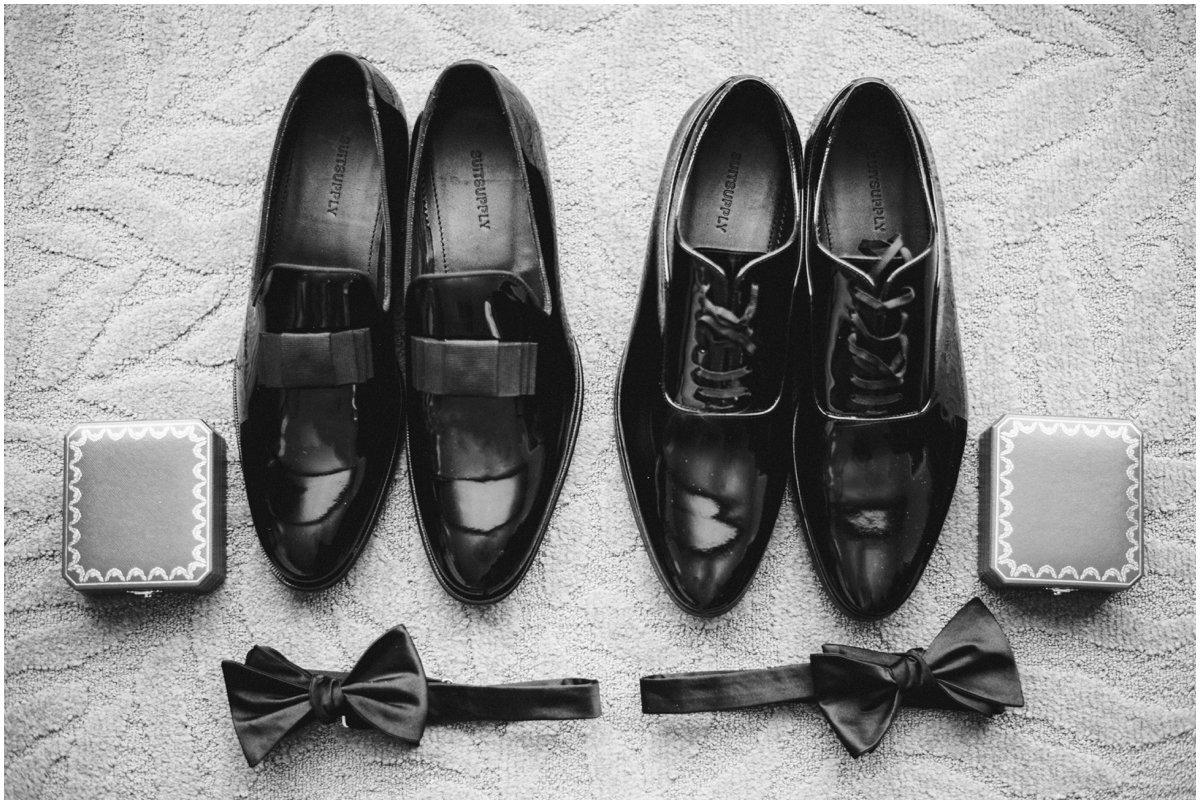Black and white photo of mens wedding shoes and bow tie