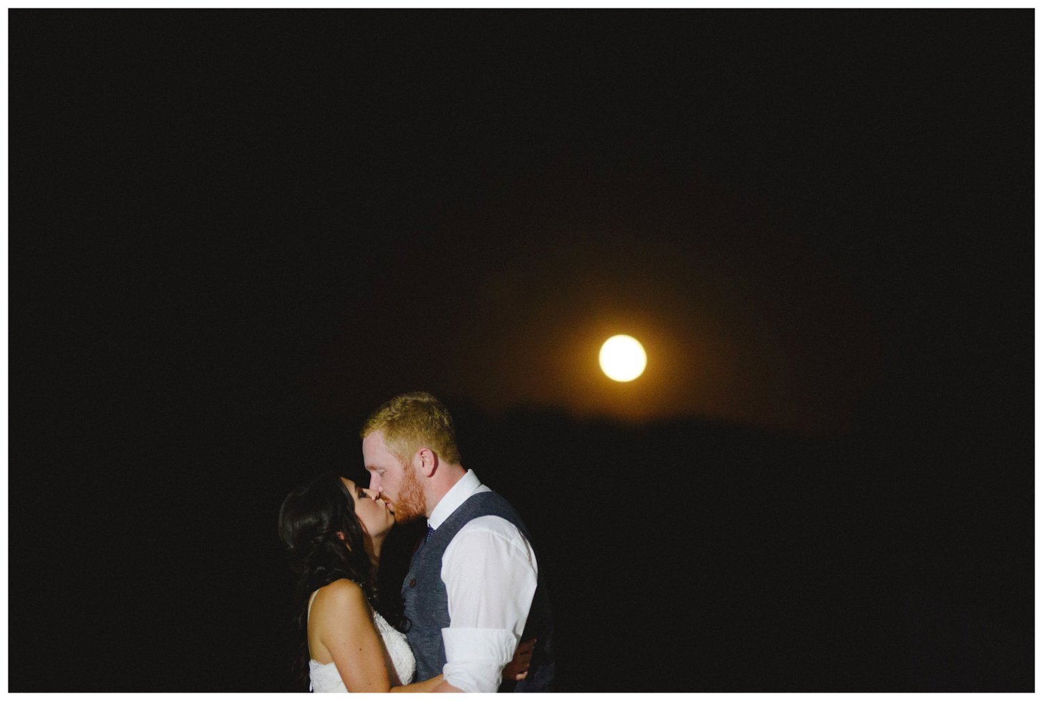 bride and groom kissing in front of a full moon at The Greens at Renton Wedding