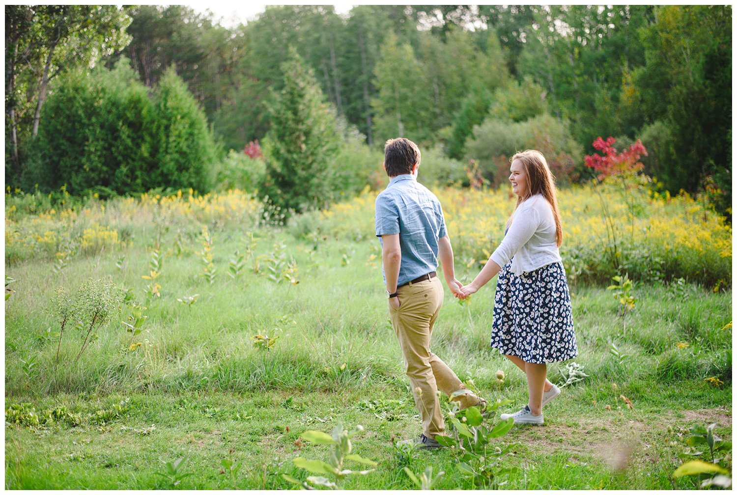 couple walking through a field at Uxbridge engagement photographer