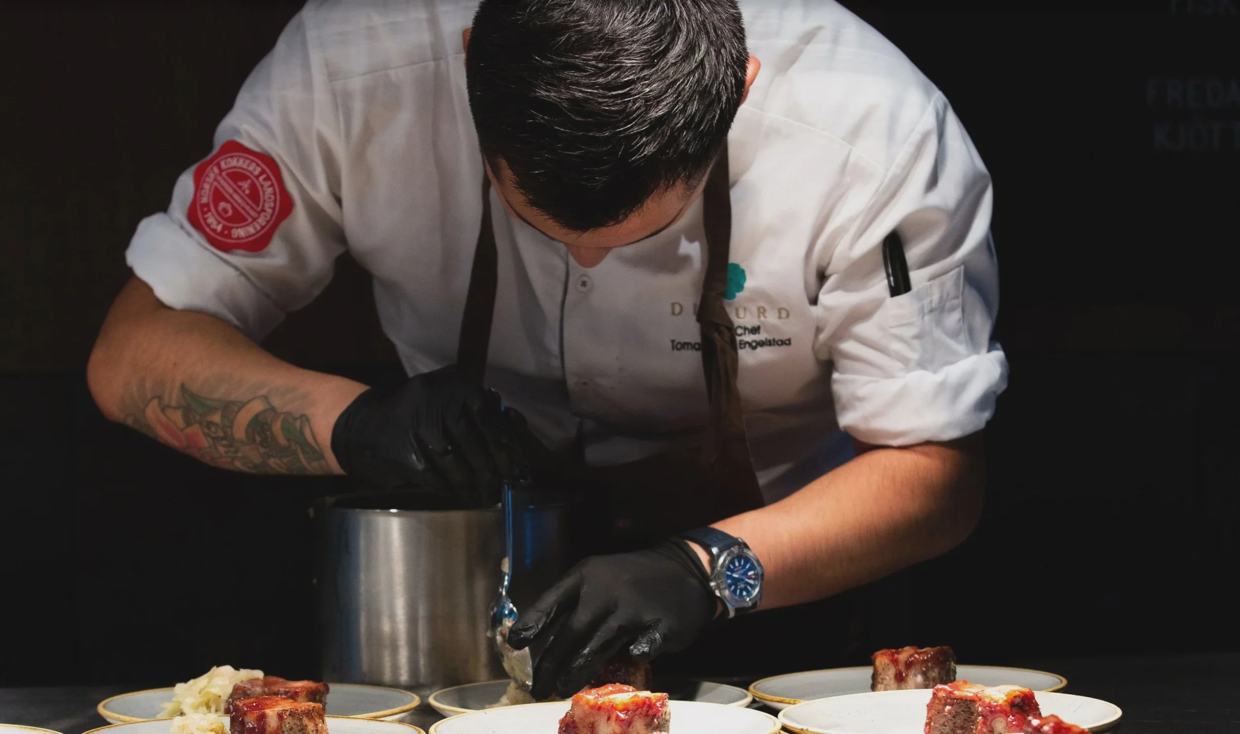 Foto av kokken Tomas fra Mat for Mons som står bøyd over mat. Fotograf: Tuva Kleven og  Thomas Larsen.