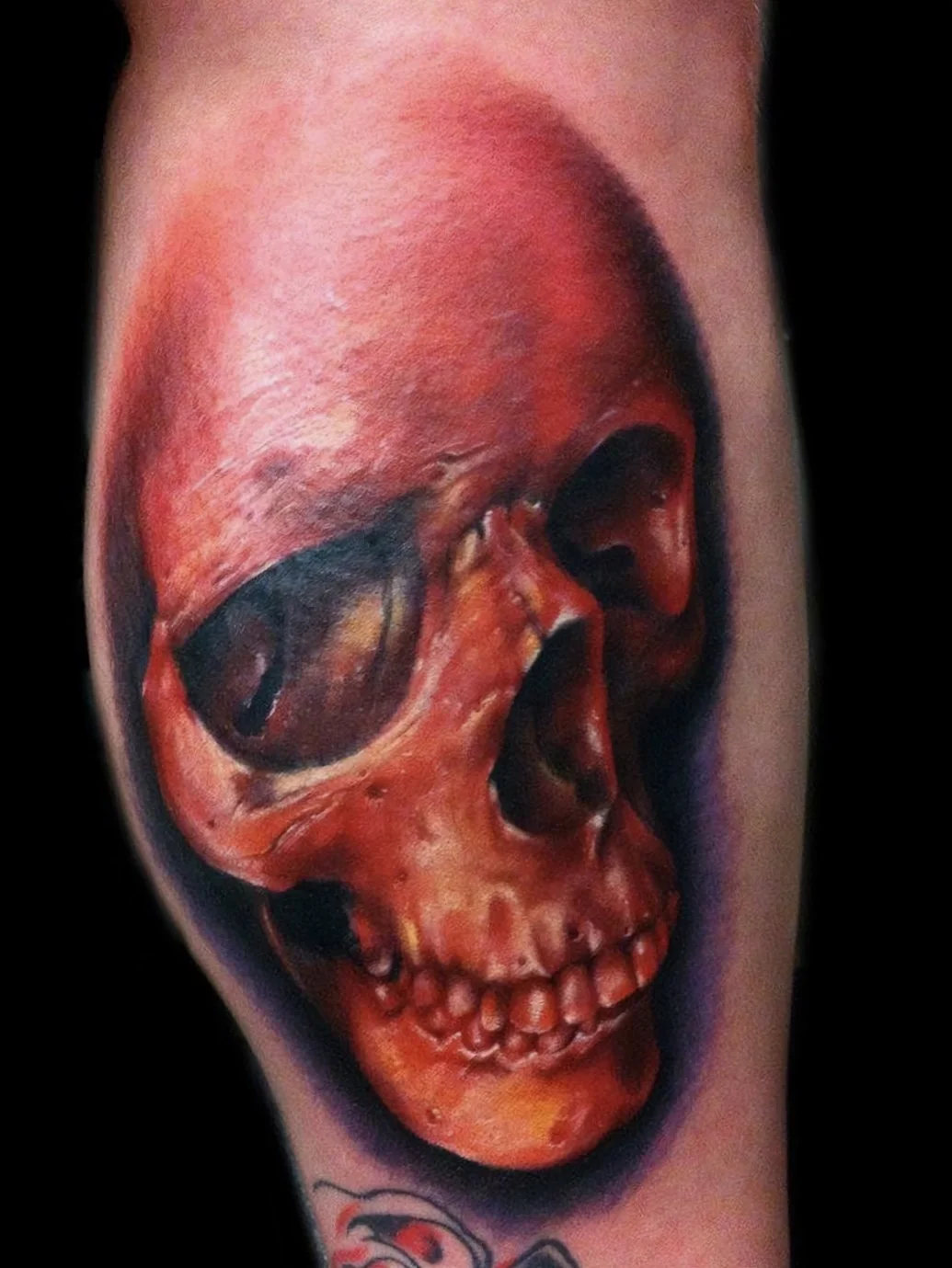 Tattoo of a realistic red skull on a person's arm.