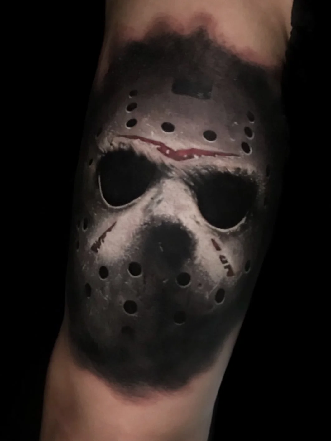Tattoo of Jason Voorhees mask from Friday the 13th on a person's arm.