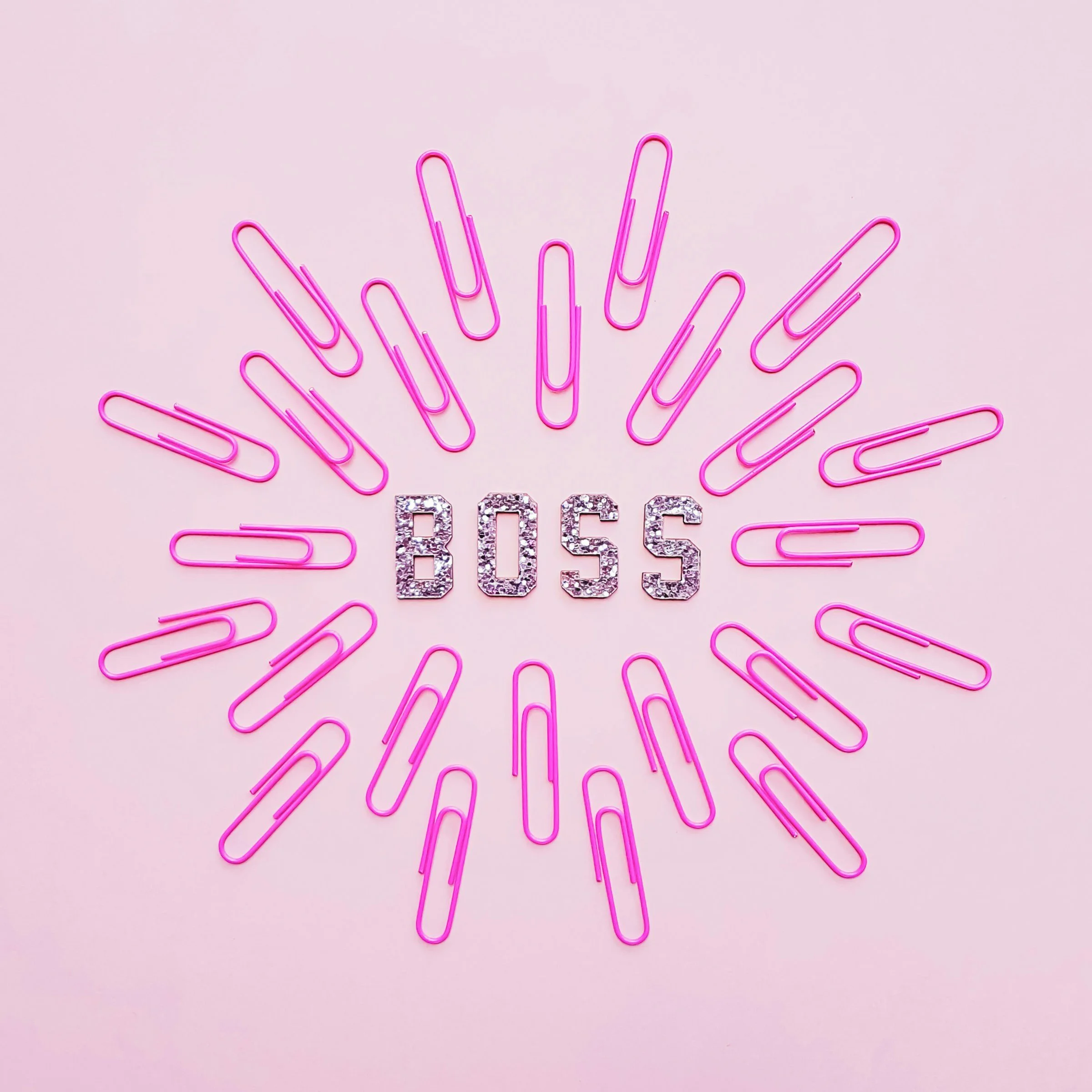 pink background, jewelled letters in the centre read "BOSS", surrounded by several pink paper clips