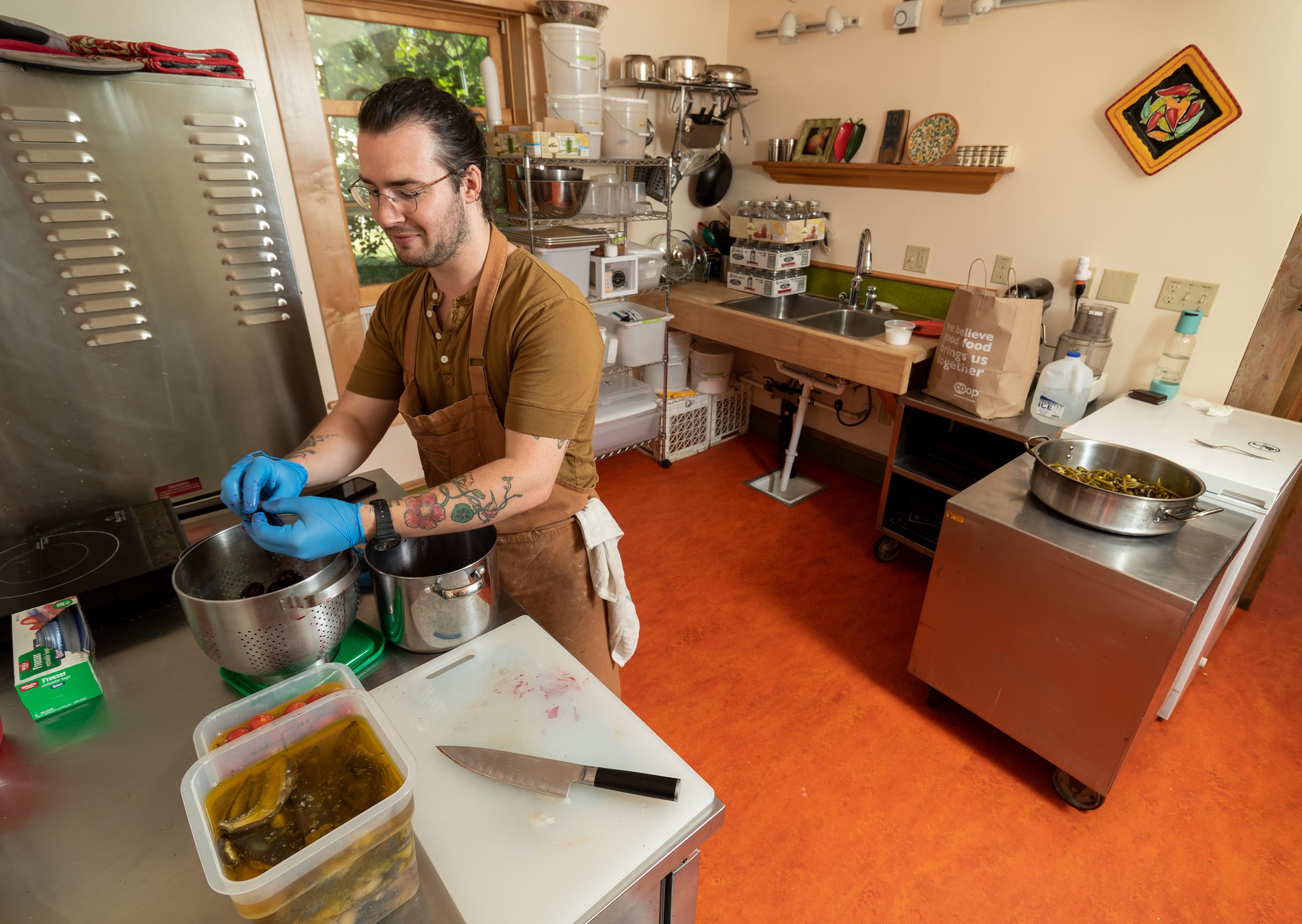 Cellar Door chef Ian Pecoraro pits pickled cherries at the Peterson Cookhouse Commercial Kitchen on Aug. 11.