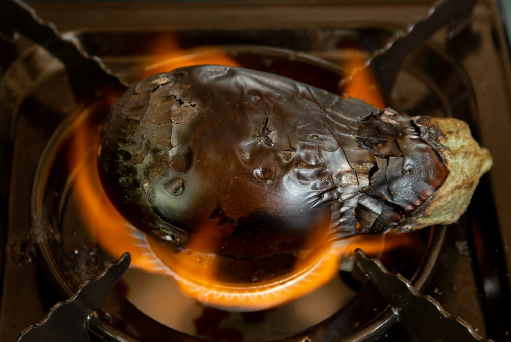 Pecoraro chars eggplant on a gas burner.