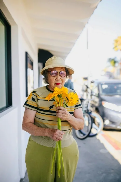 An older woman holding a bouquet of sunflowers.
