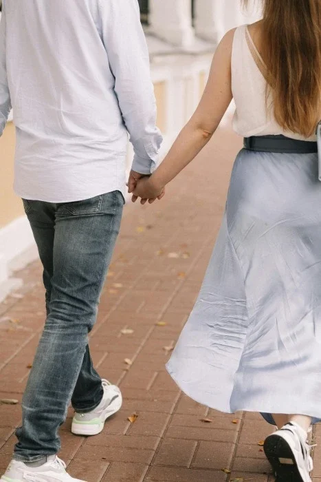 A couple holding hands and walking outside.