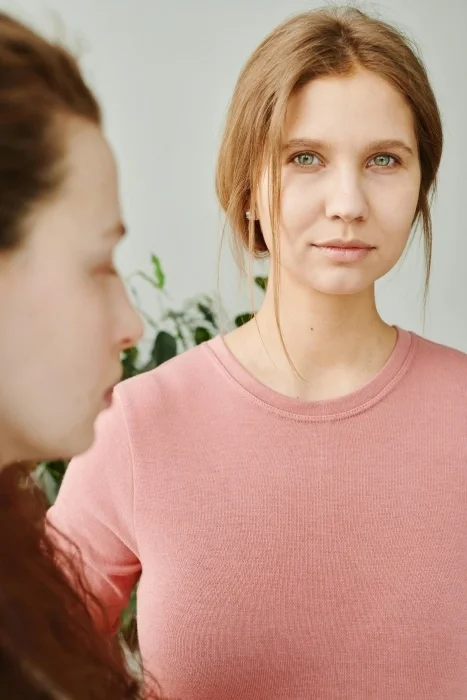 Two women standing together. One is smiling at the camera.