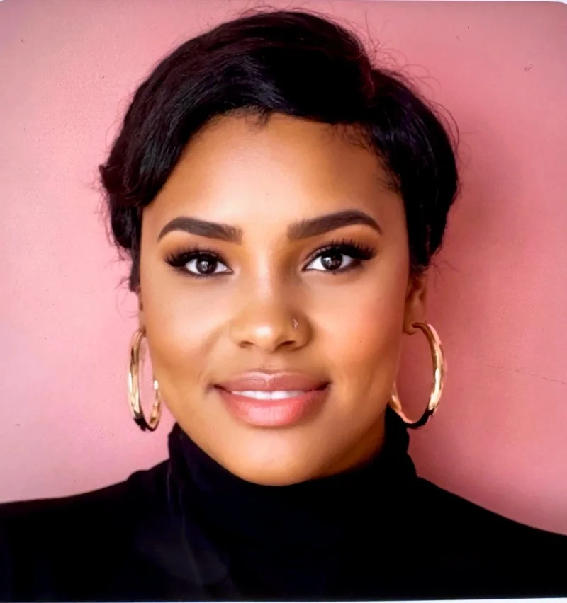 Portrait of a woman with short black hair, wearing hoop earrings and makeup.
