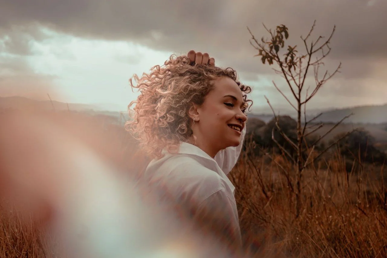 smiling-ethnic-woman-in-countryside-field-at-sunset