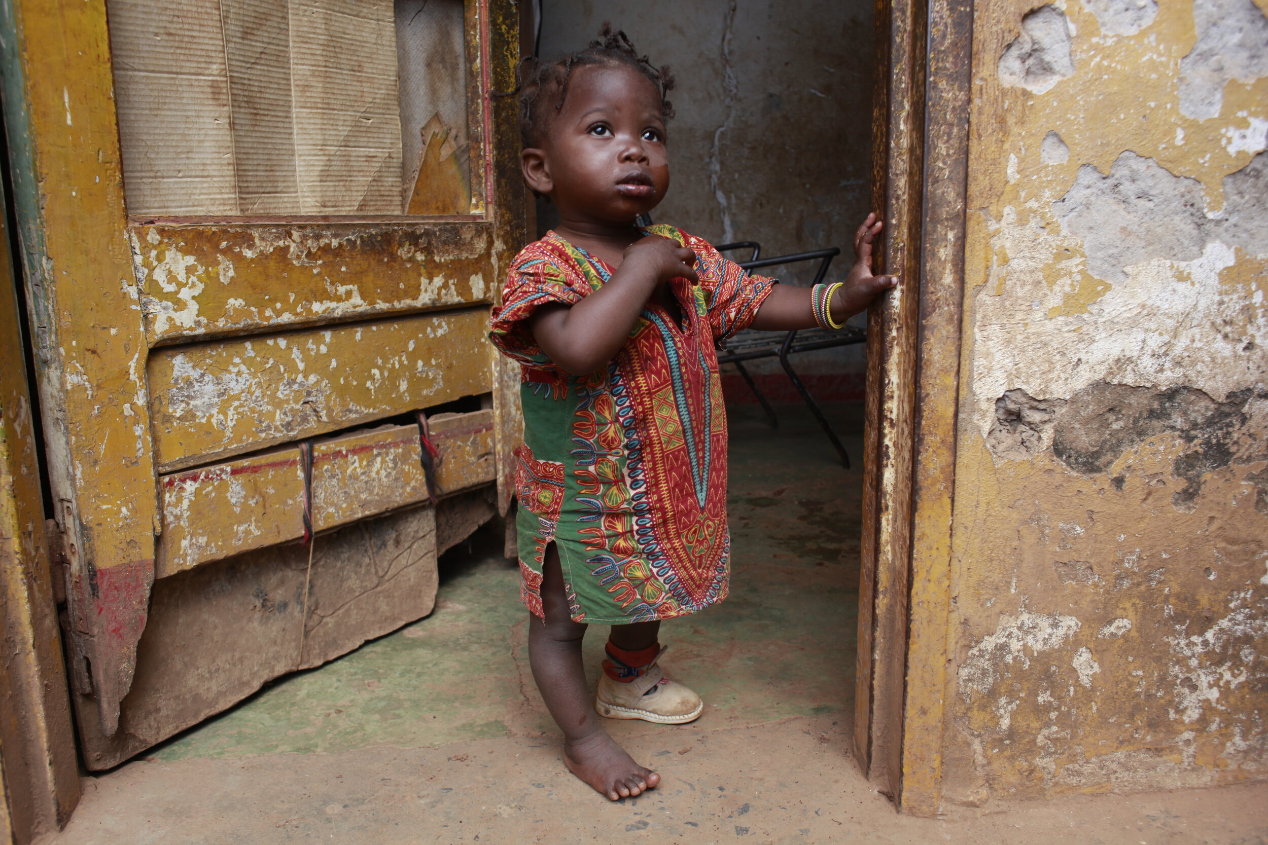  Tabita, 1 year and 3 months, stands outside her door. Her family is  using a bednet which was distributed  to help prevent against Malaria in the Tshamilemba health district of Lumbabashi, Democratic Republic of Congo 