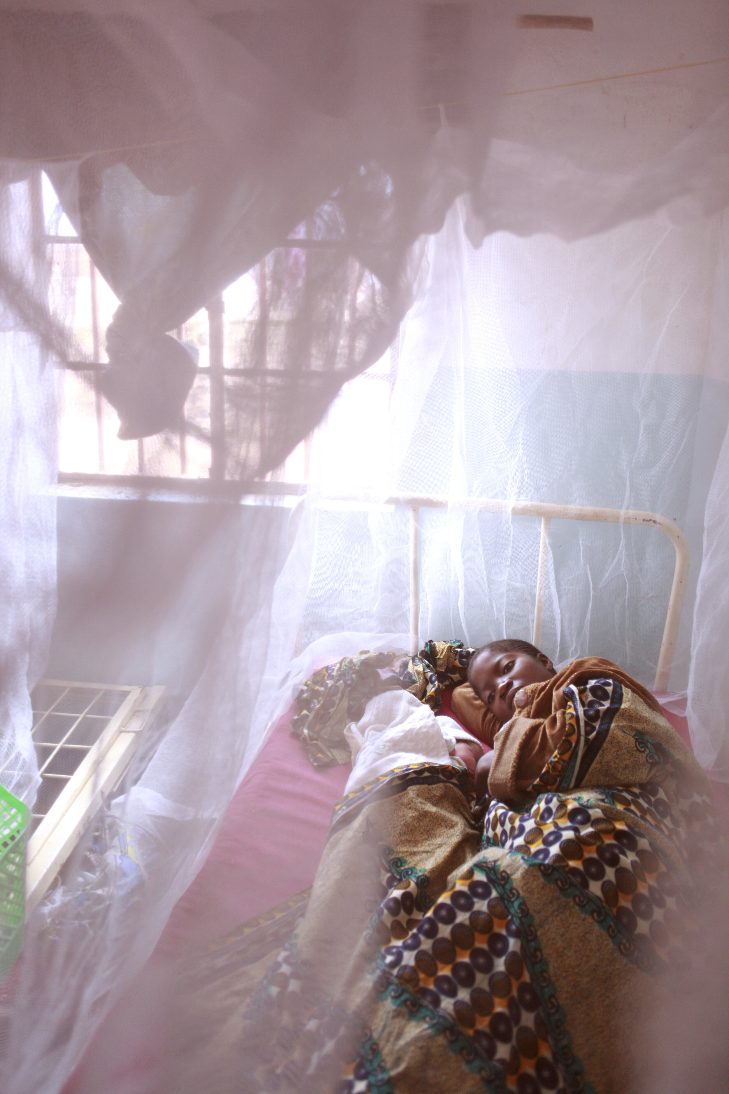  Louise Arun, with her newborn who is not yet named, under a  bednet at a maternity hospital in the Tshamilemba health district of Lumbabashi, Democratic Republic of Congo. Bednets are used to help prevent Malaria by protecting people from the mosqui