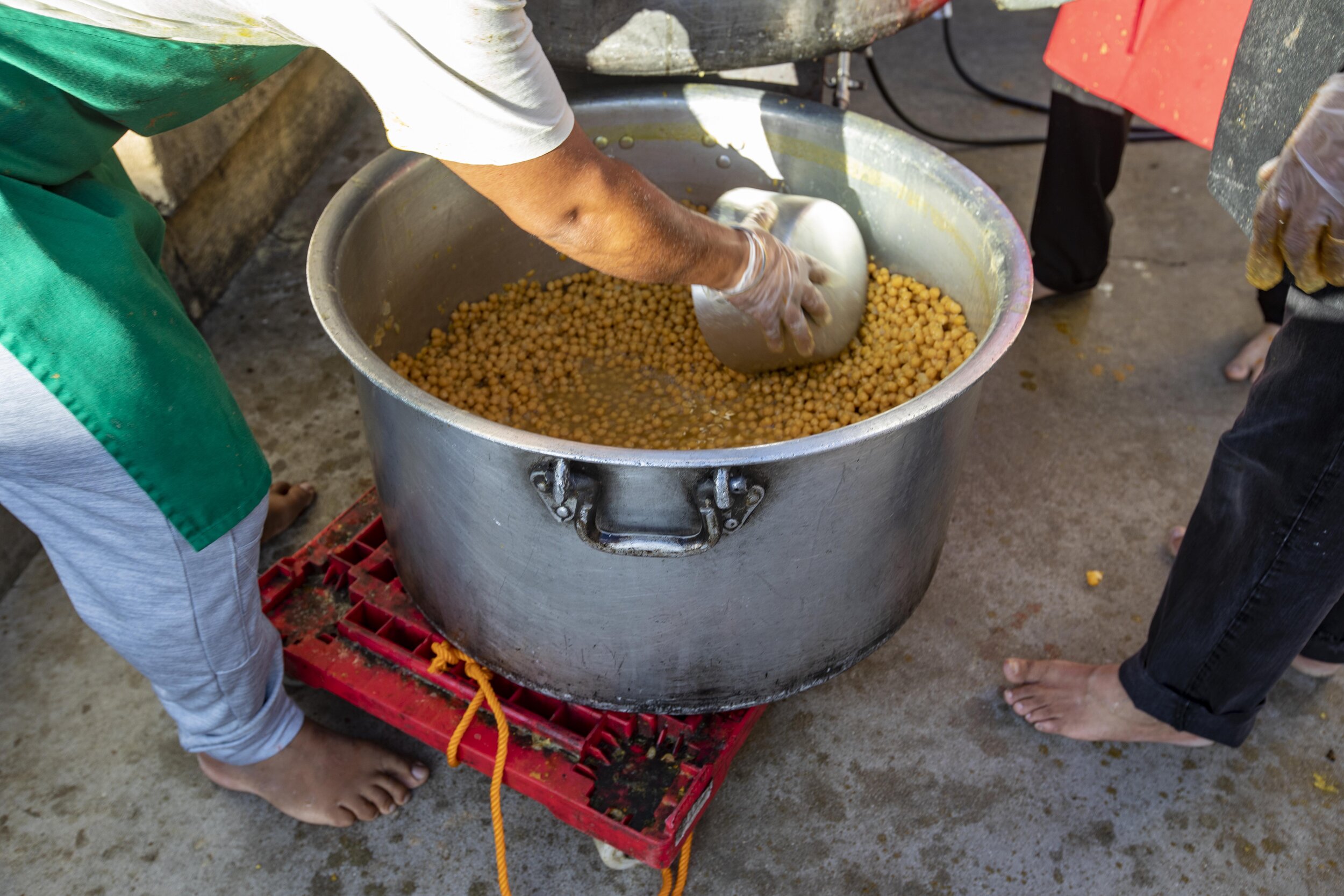  Volunteers add chickpeas to a pot at Khalsa Care Foundation. The Sikh community is working with the mayor's office and Department on Disability and making 3,000 meals daily. They have 50-55 volunteers that show up Monday through Friday to make meals