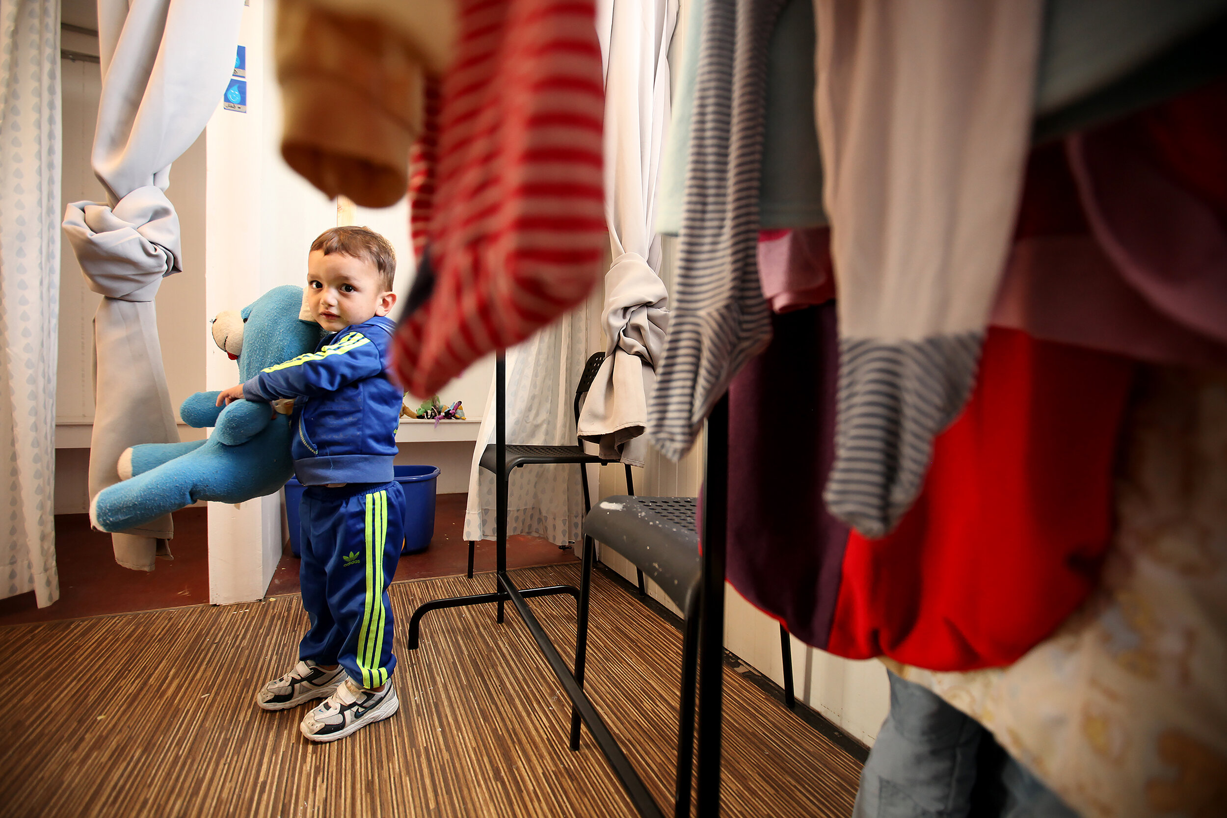  A young boy plays with toys  while his mom is shopping at the  Drop in the Ocean shop at Skaramagas refugee camp in Athens, Greece. 