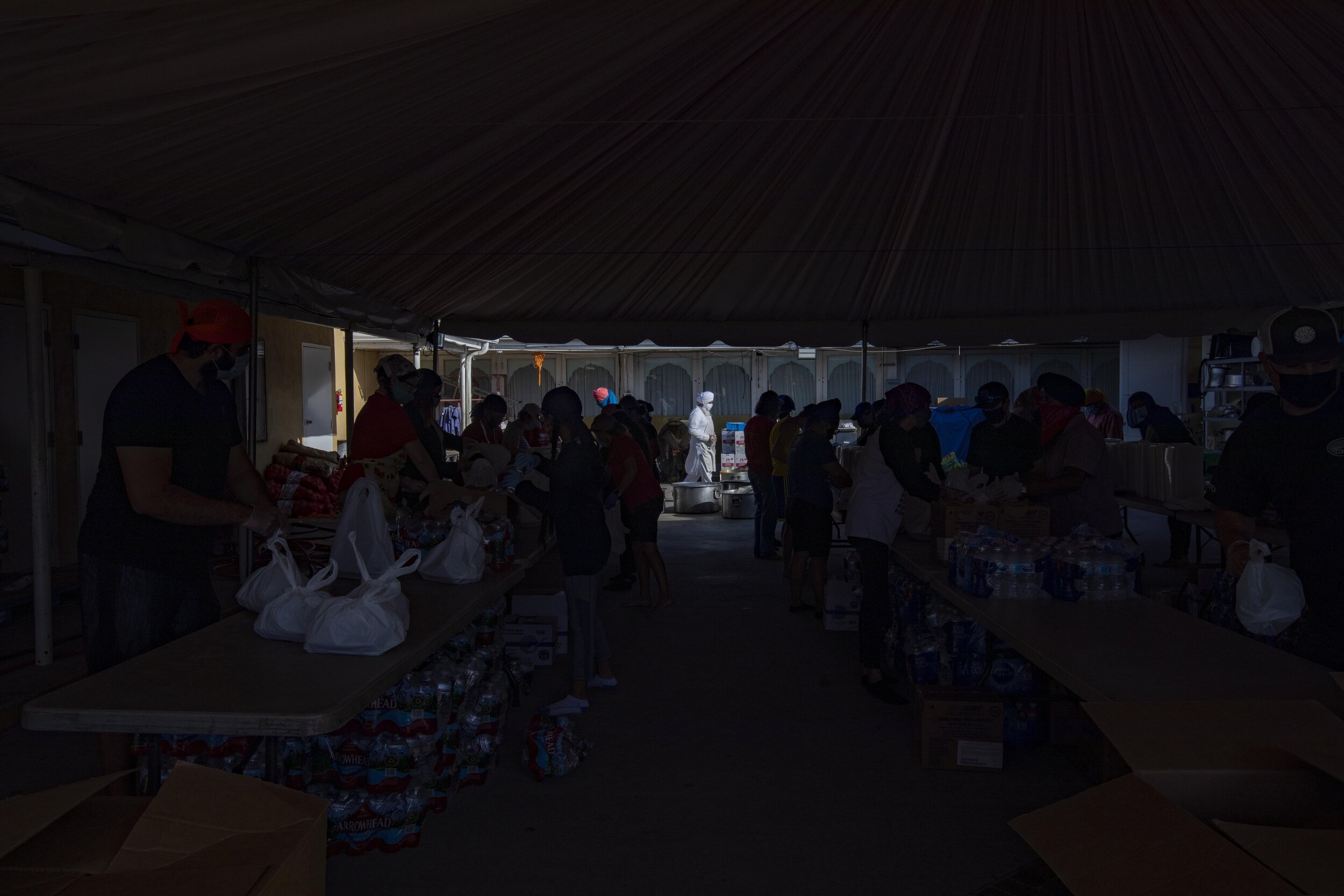  Manjeet Singh walks by the tent where volunteers are packaging 3,000 meals to be distributed to people with disabilities and others in need at Khalsa Care Foundation. They have 50-55 volunteers that show up Monday through Friday to make and package 