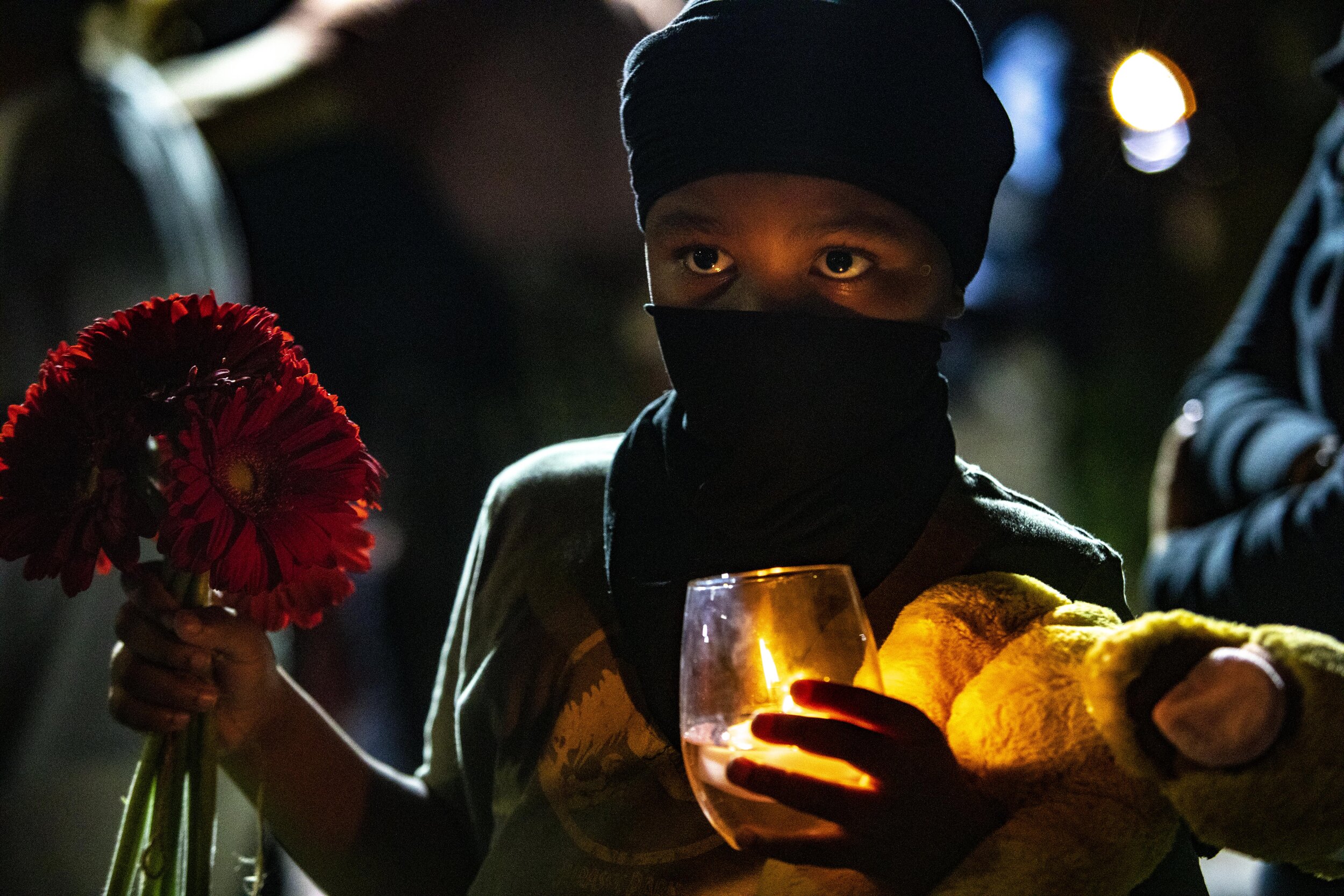 A child holds flowers and a candle outside the federal building as members of the Los Angeles Afghan community held a candlelight vigil in response to the Taliban taking control of Afghanistan. 