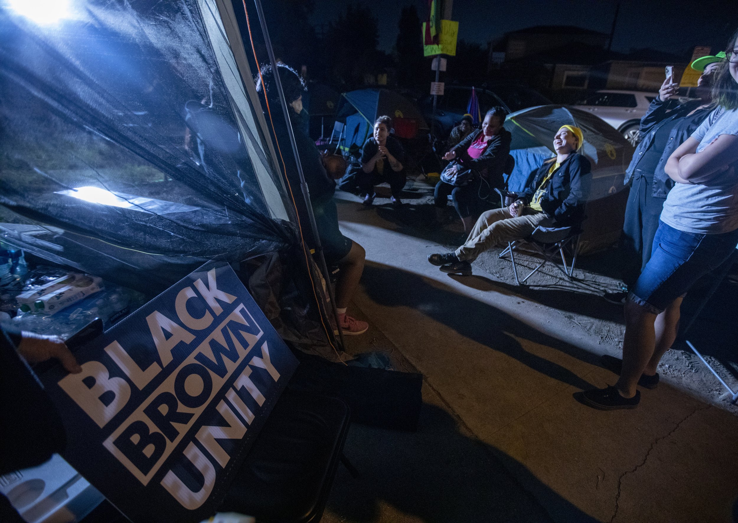  Julia Rich (center in the yellow hat) of White People for Black Lives shares a laugh with Black Lives Matter protesters and their supporters who have set up an encampment near city council member Kevin de Leon's house in Eagle Rock. They have been t