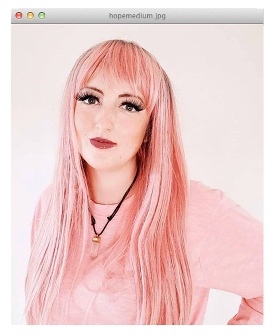Hope Carpenter with long pink hair and bangs in a pink sweater against a light background