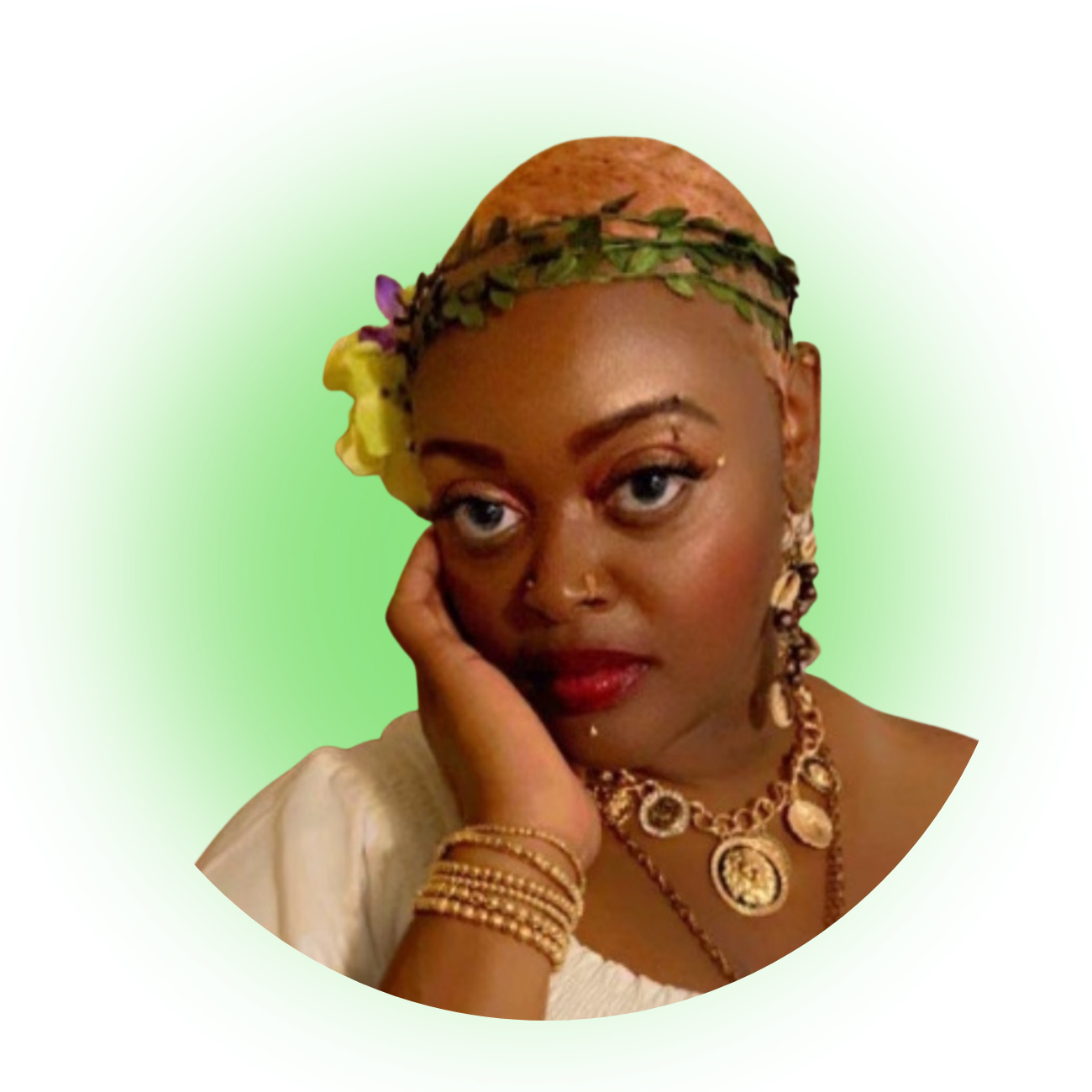 Shakeyna Lumsden with gold jewelry, a headband of leaves, and flowers on her head, resting her face on her hand against a white background with a green iridescent glow.