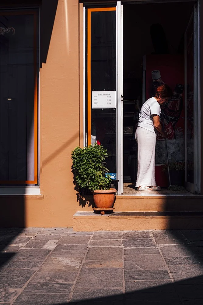 Lady cleaning her shop in the morning sun in Rodos Greece