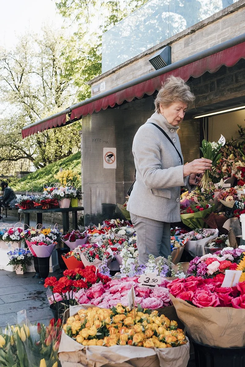Woman buying flowers in old town Tallinn gates. Photos from Estonia