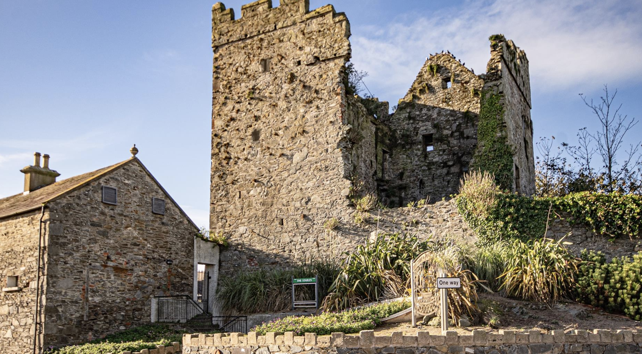 Ruins of a historic stone church or cathedral with arches and tall spires against a bright blue sky.