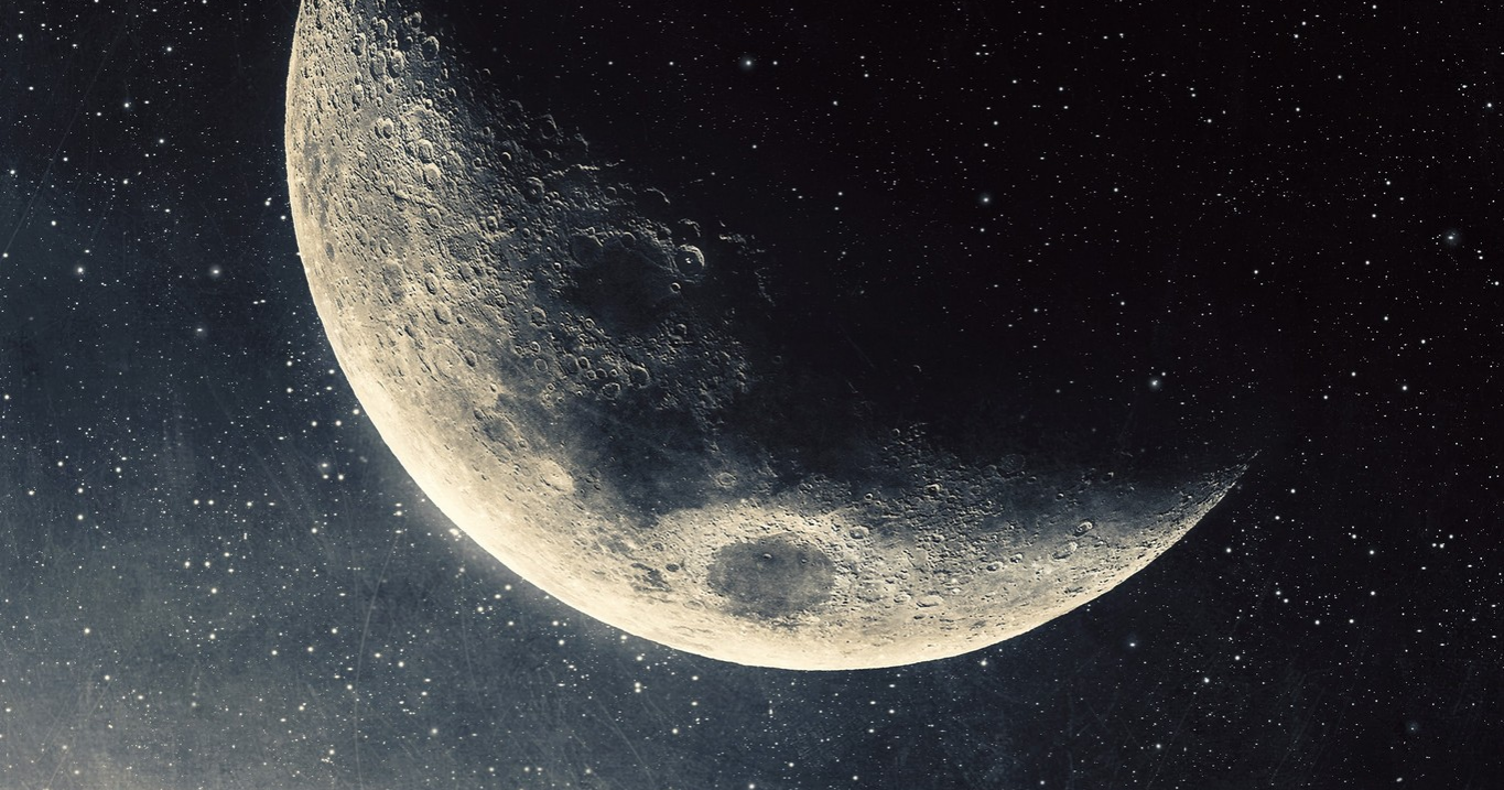 A crescent moon in the night sky, illuminated from the bottom.