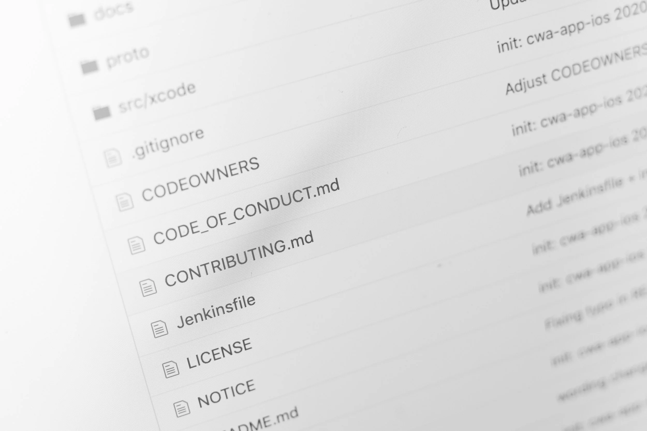 Close-up of a computer screen displaying a list of folders and files related to coding, with some text including '.gitignore', 'CODEOWNERS', and 'CODE_OF_CONDUCT.md' visible.