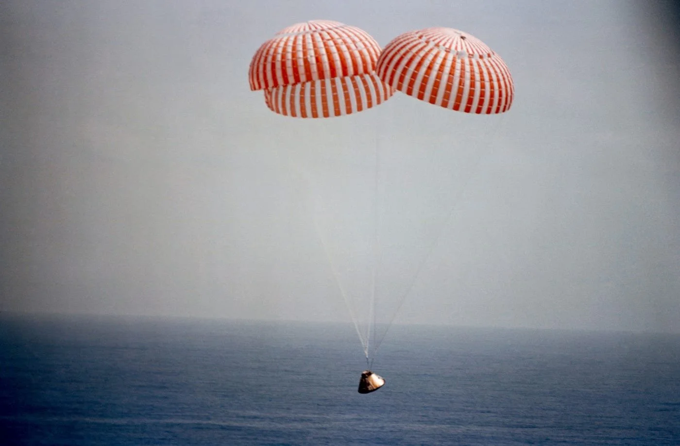 A person being pulled by three parachutes over the ocean.