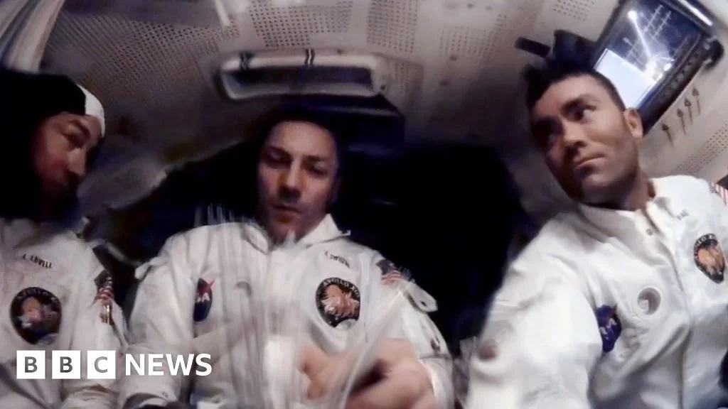 Astronauts in space suits inside spacecraft, preparing for launch.